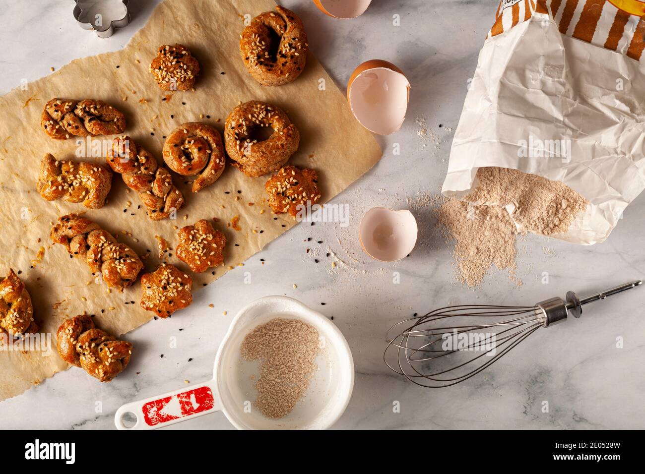 Flat Lay image de la pâtisserie faite à la main avec de la farine de blé entier, de l'oeuf et décoré avec des graines de sésame et de pavot. Ils sont sur le papier de cuisson refroidissant au-dessus de mar Banque D'Images