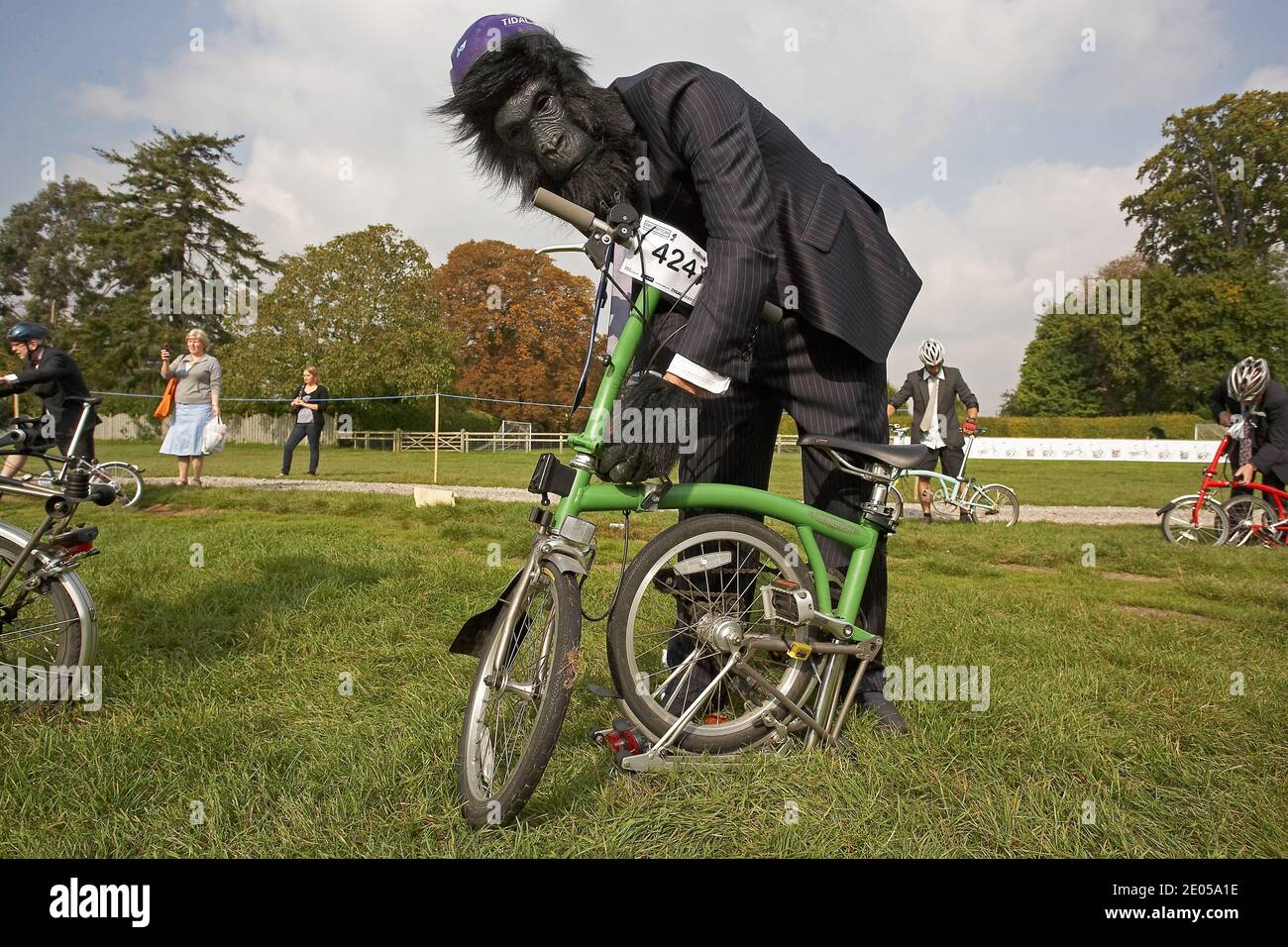 Participant portant un costume de singe poussant sa bicyclette pliante Brompton aux Championnats du monde de Brompton, qui se tiennent au Palais de Blenheim, Royaume-Uni . Banque D'Images