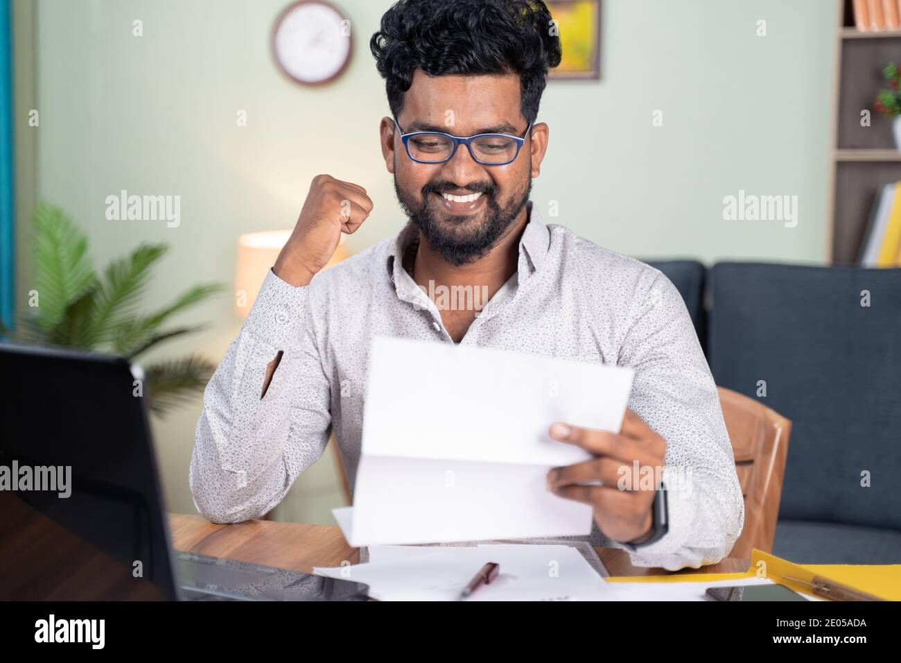 Jeune homme lisant la lettre de papier se sentant surjoyé par de bonnes nouvelles serré poing - concept de nouvelle offre d'emploi ou de promotion, admission à l'université et prêt Banque D'Images