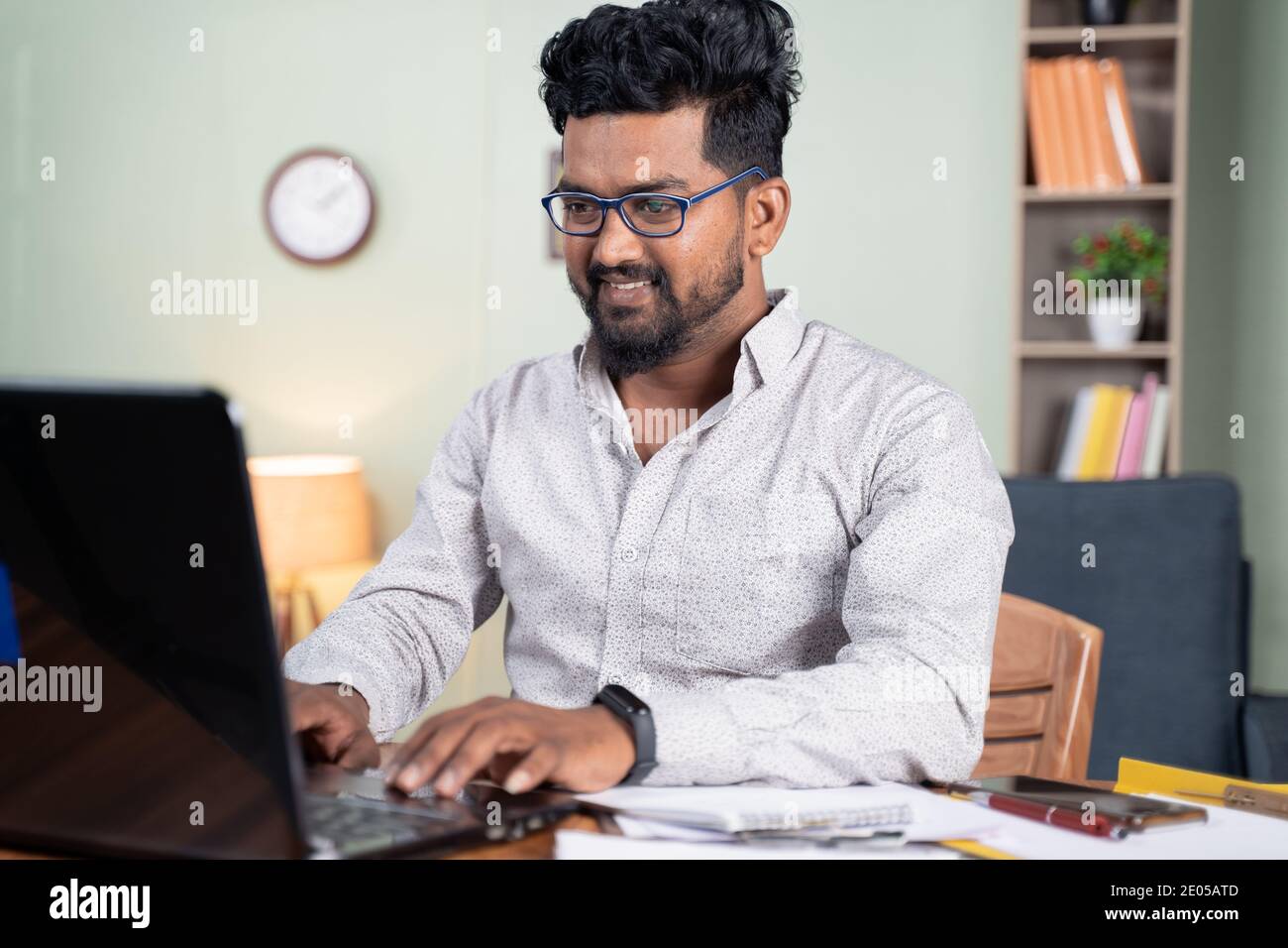 Un jeune homme heureux qui travaille sur un ordinateur portable à la maison - concept d'employé informatique professionnel au travail à domicile. Banque D'Images