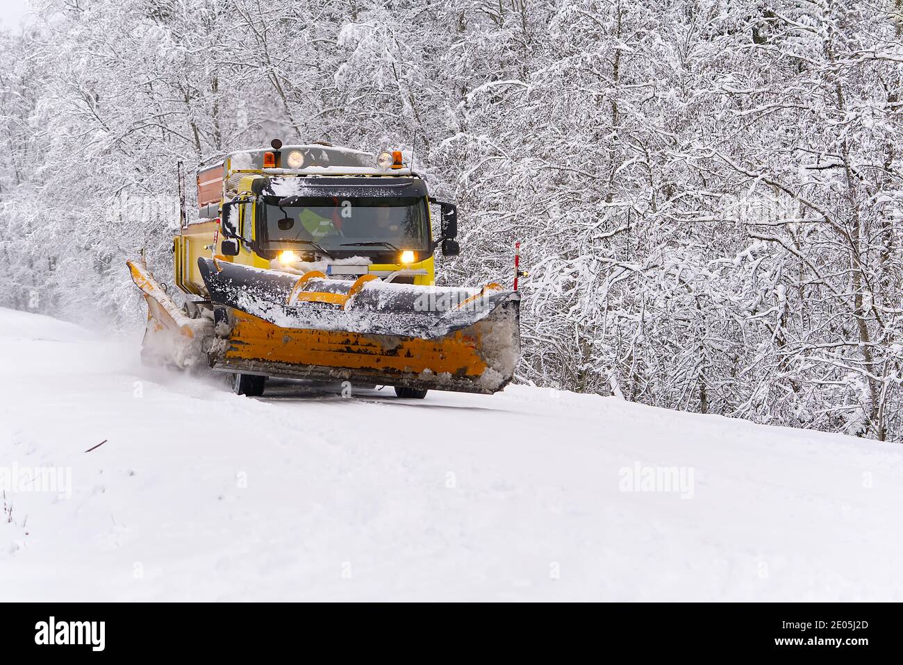 Une voiture souffleuse à neige élimine la neige de la forêt le matin d'hiver. Chasse-neige camion de nettoyage de la route blanche glacée Banque D'Images