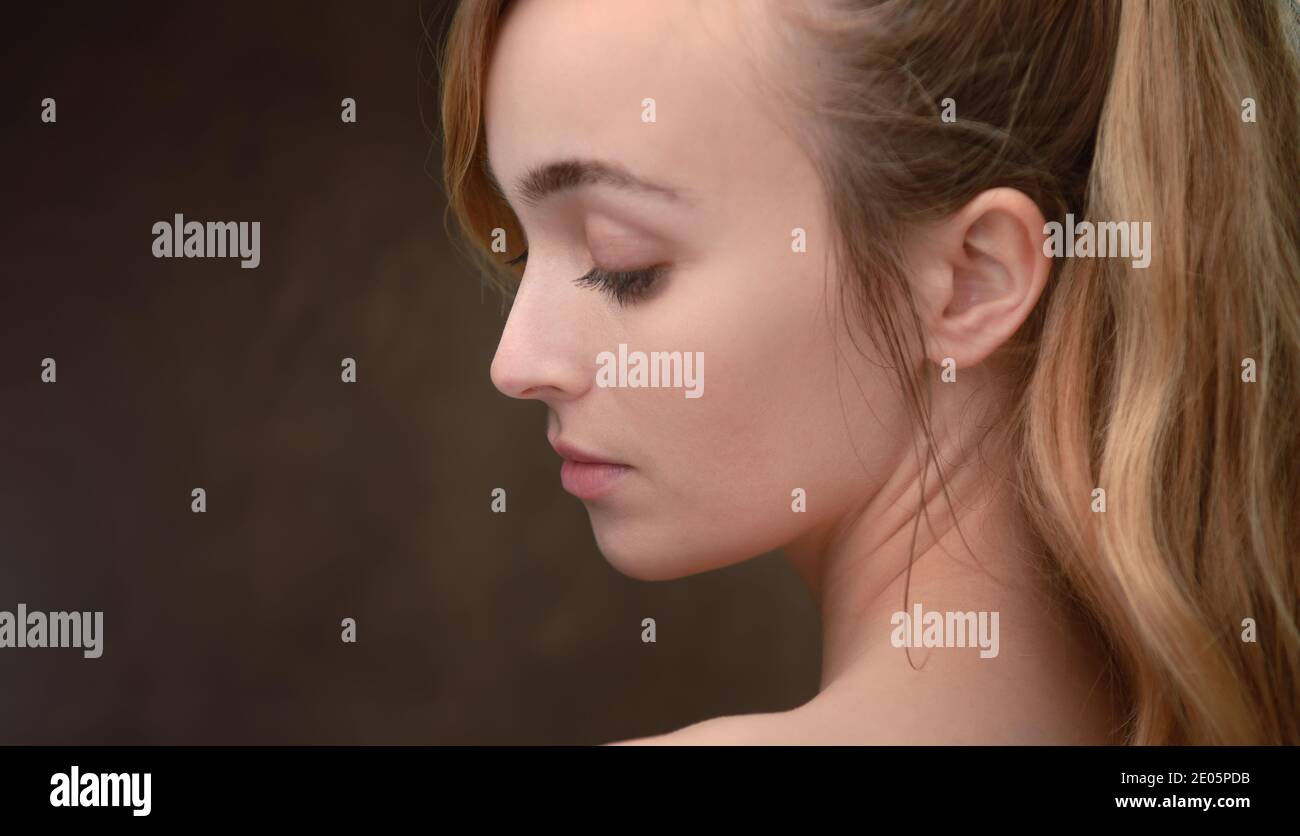 Un portrait de beauté paysage gros plan d'une jeune femme naturellement belle (20) regardant sur le côté et vers le bas avec l'espace de copie. Banque D'Images