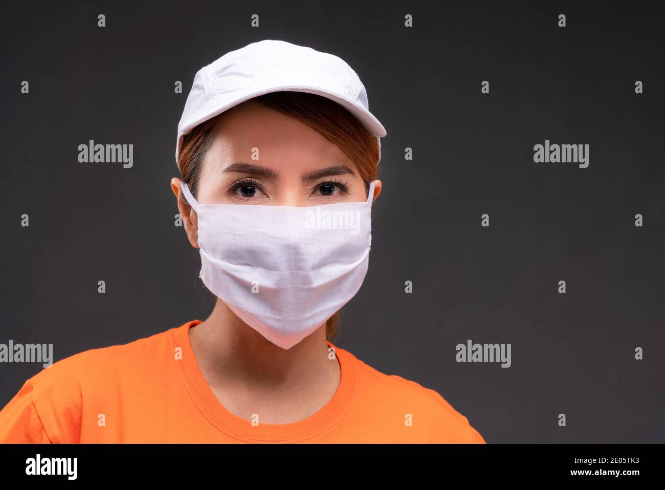 Gros plan sur la livraison femme asiatique ou port de messagerie un chapeau orange et un uniforme masqué dans la prévention du propagation du concept de la maladie du coronavirus Banque D'Images