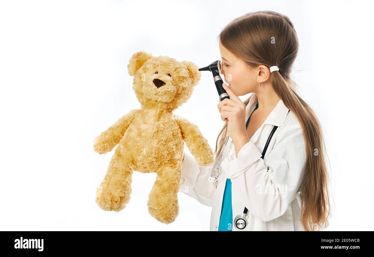Une fille caucasienne jouant avec son patient ours en peluche dans un jeu de docteur. Enfant utilisant de l'ophtalmoscope Banque D'Images