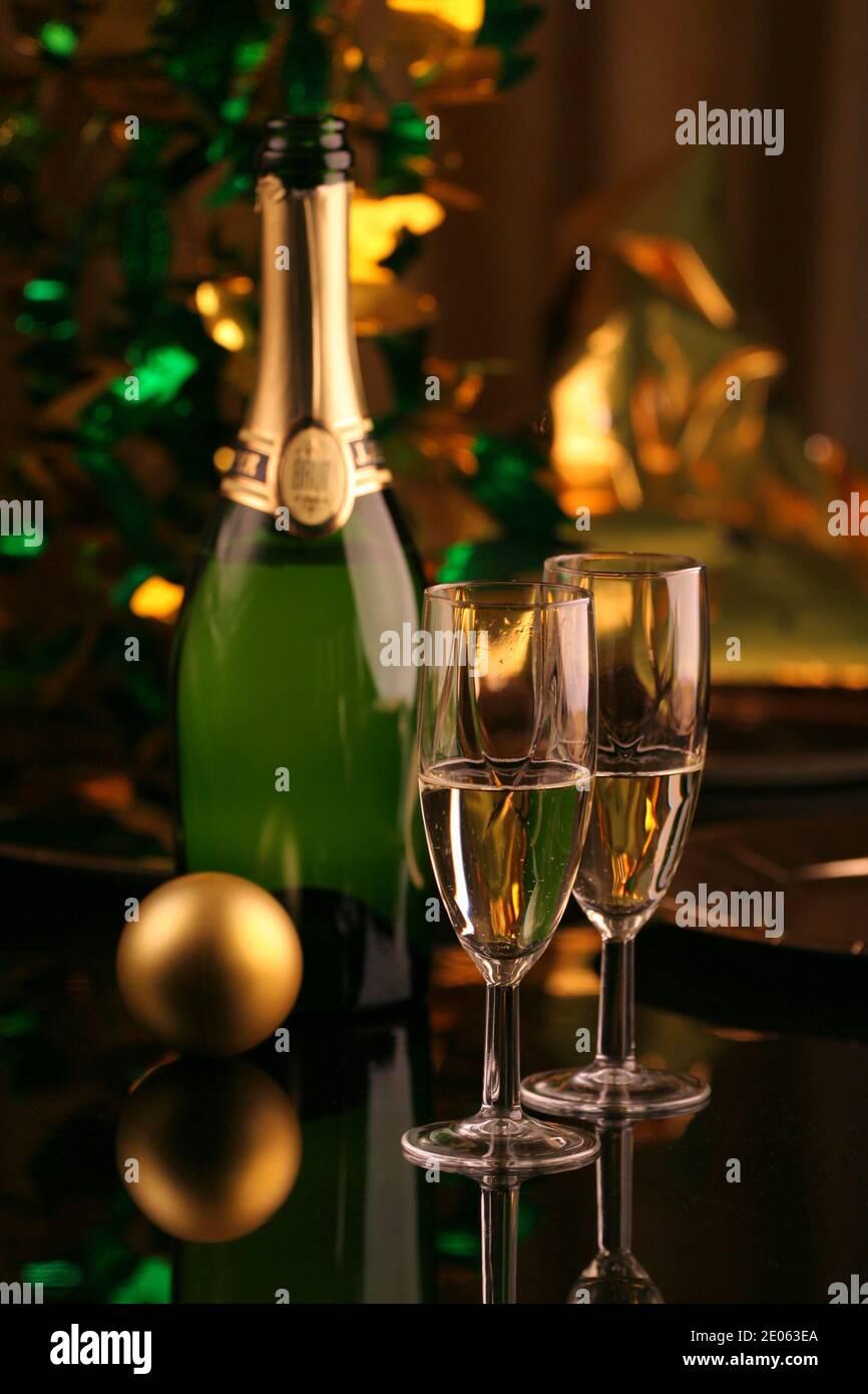 Deux verres de champagne avec une bouteille et un Noël boule et ruban doré sur fond sombre Banque D'Images