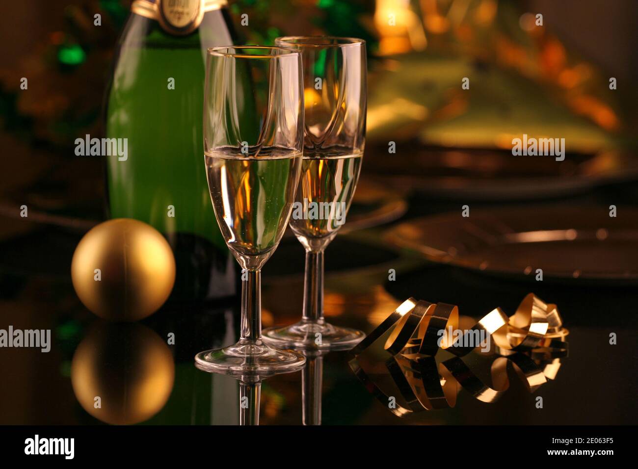 Gros plan de deux verres de champagne avec une bouteille et Une boule de Noël et un ruban doré sur fond sombre Banque D'Images