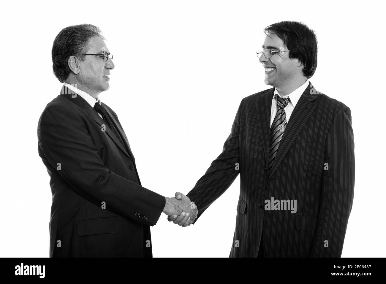 Voir le profil de professionnels jeunes et senior Persian businessman smiling and shaking hands Banque D'Images