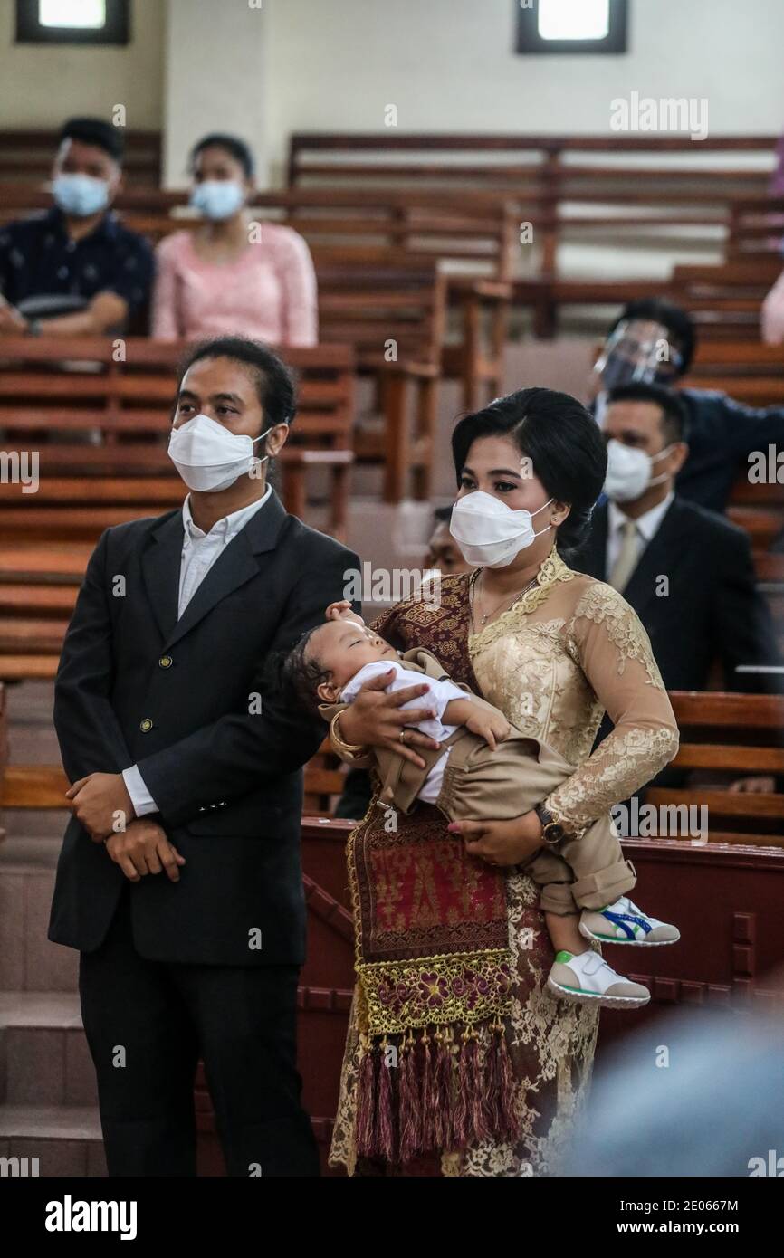 Medan, Sumatera du Nord, Indonésie. 26 décembre 2020. Une femme portant un masque facial est vue porter son enfant au prêtre pour la cérémonie de baptême à l'église protestante Batak Karo, à Medan. Crédit : Kartik Byma/SOPA Images/ZUMA Wire/Alay Live News Banque D'Images