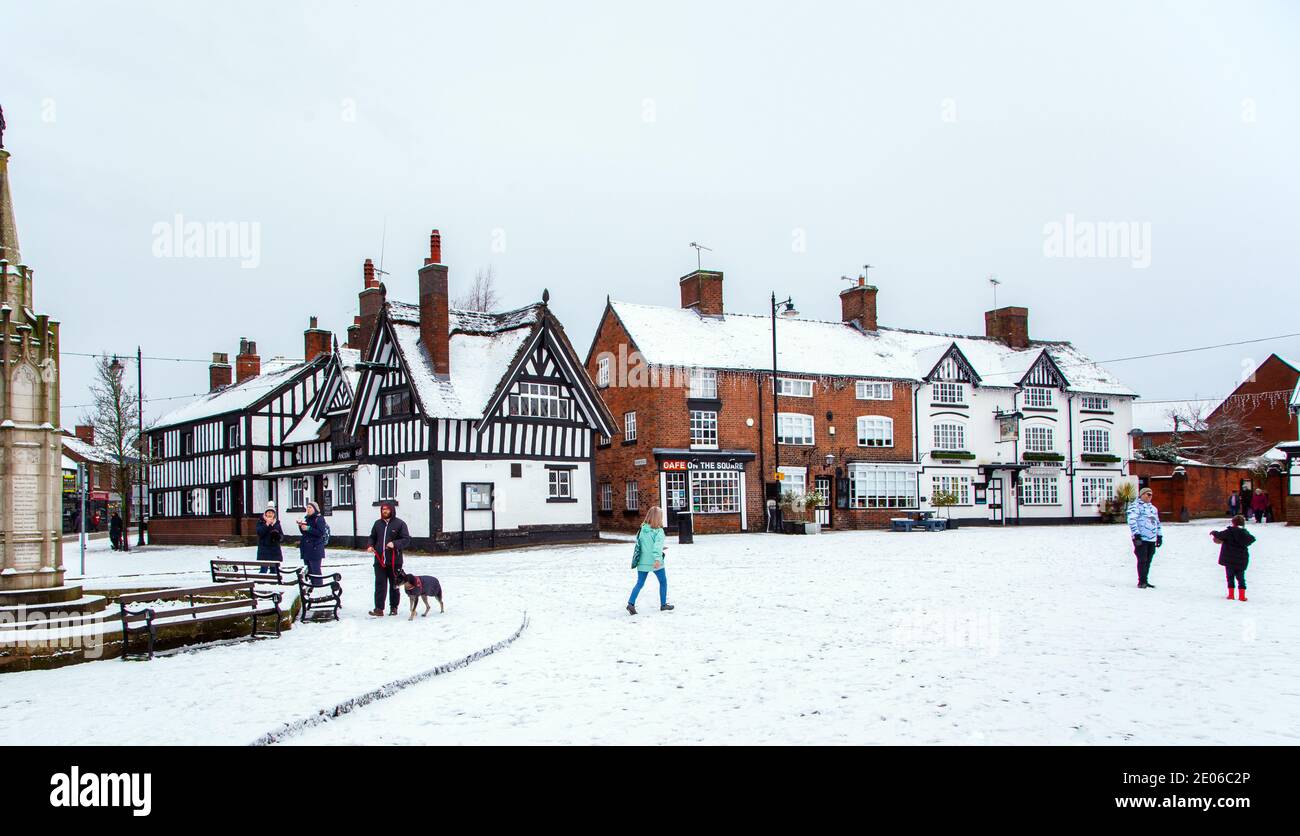 Place du marché enneigée à Sandbach à Cheshire dans le hiverner avec le mémorial de guerre du cénotaphe et le noir et white half timbered coaching inn Banque D'Images