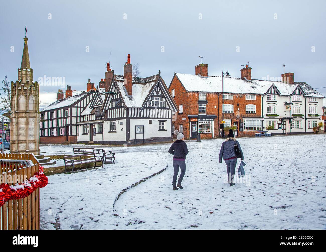 Place du marché enneigée à Sandbach à Cheshire dans le hiverner avec le mémorial de guerre du cénotaphe et le noir et white half timbered coaching inn Banque D'Images