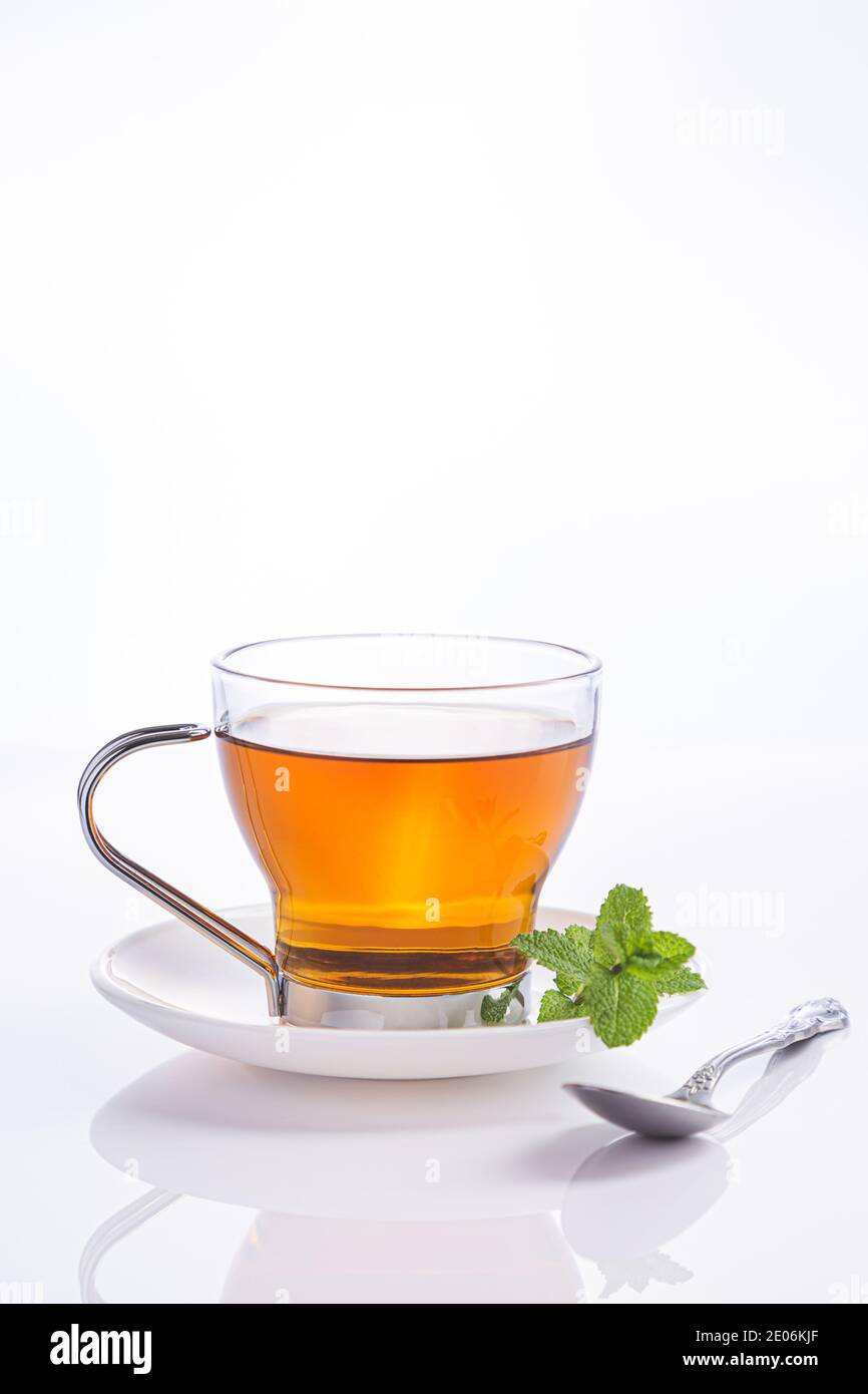 Infusion de menthe poivrée dans du verre de cristal et des feuilles de menthe fraîche, isolées sur fond blanc. Banque D'Images