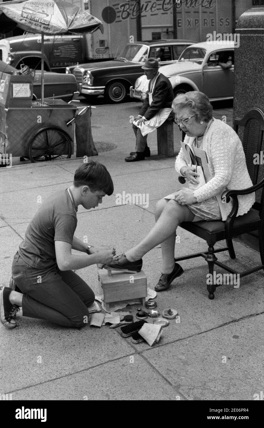 Shoeshine garçon des années 1970 États-Unis. Adolescent travaillant à faire de l'argent de broche supplémentaire étant un garçon de cirage de chaussures, à polir un client, une femme plus âgée chaussures en cuir. Manhattan, New York 1972 USA HOMER SYKES Banque D'Images