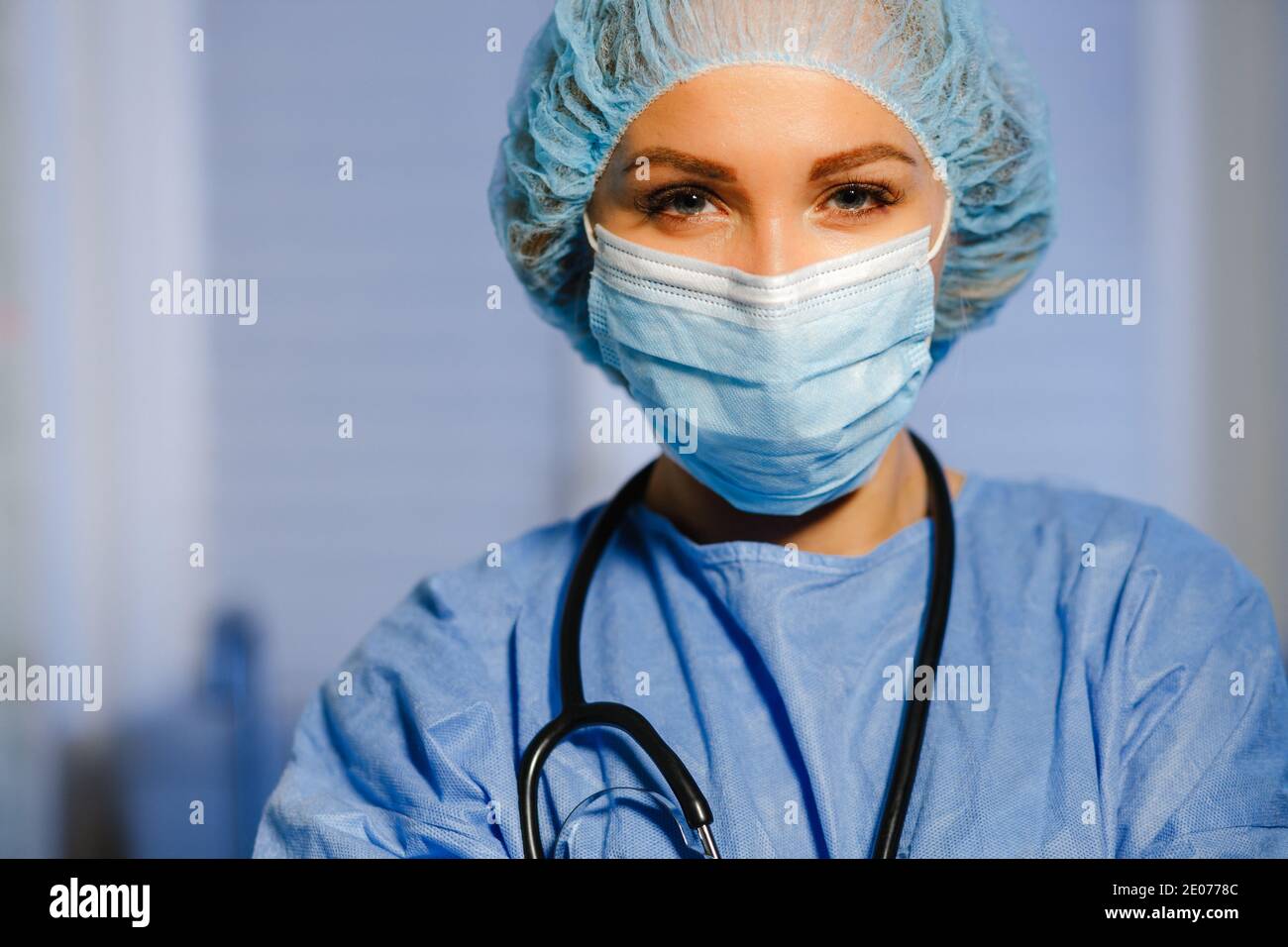 Médecin femme sérieux en combinaison de protection chirurgicale et masque regardant chez vous pendant votre visite à domicile Banque D'Images