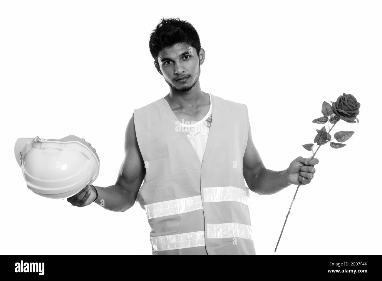 Beau jeune homme indien construction worker holding casque de sécurité et rose rouge prêt pour la Saint-Valentin Banque D'Images