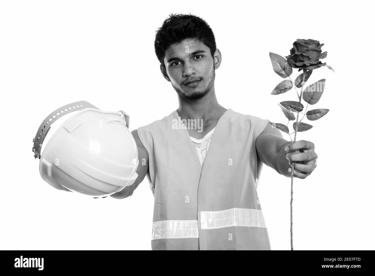 Beau jeune homme indien construction worker donner casque de sécurité et rose rouge prêt pour la Saint-Valentin Banque D'Images