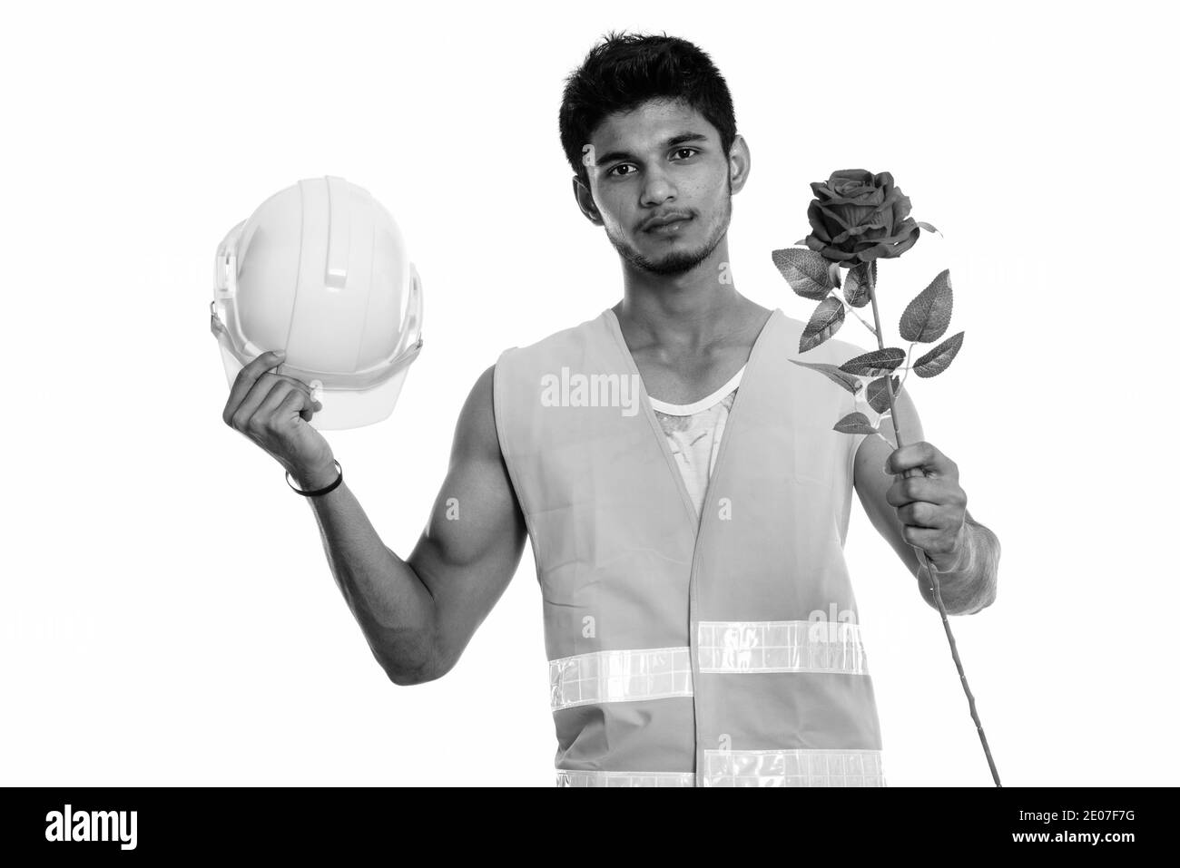 Beau jeune homme indien construction worker holding casque de sécurité et donner rose rouge prêt pour la Saint-Valentin Banque D'Images