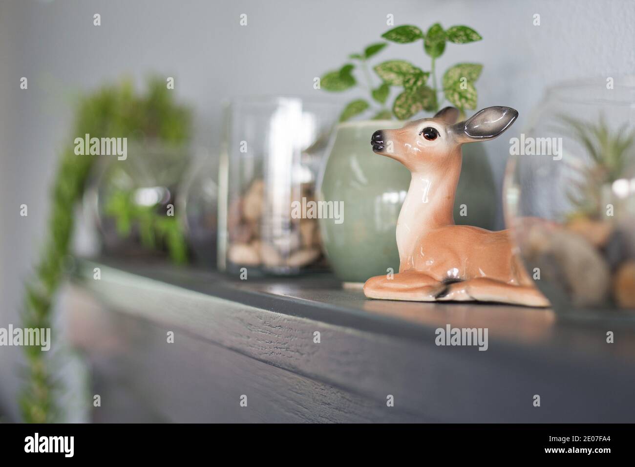 Plantes de maison et une figurine de cerf vintage sur un manteau. Banque D'Images