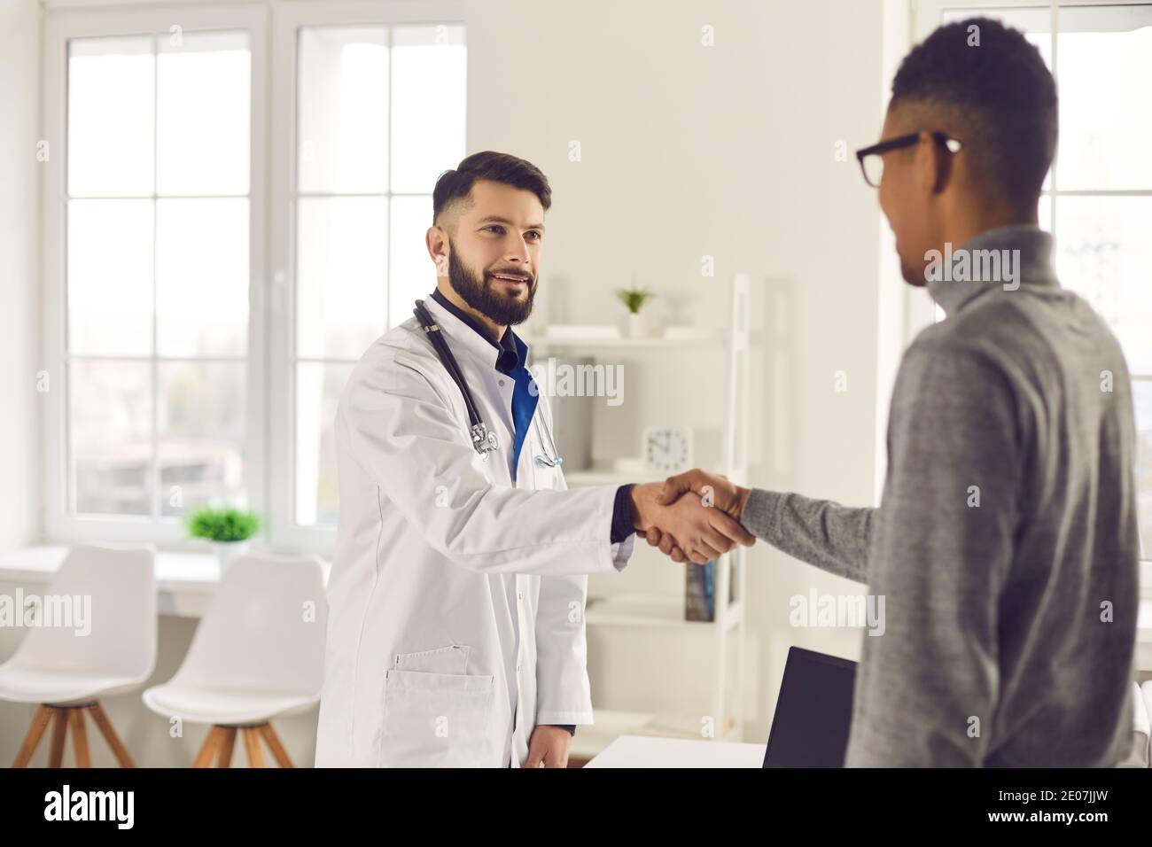 Un jeune médecin sympathique accueille son patient dans son bureau à la clinique ou l'hôpital Banque D'Images