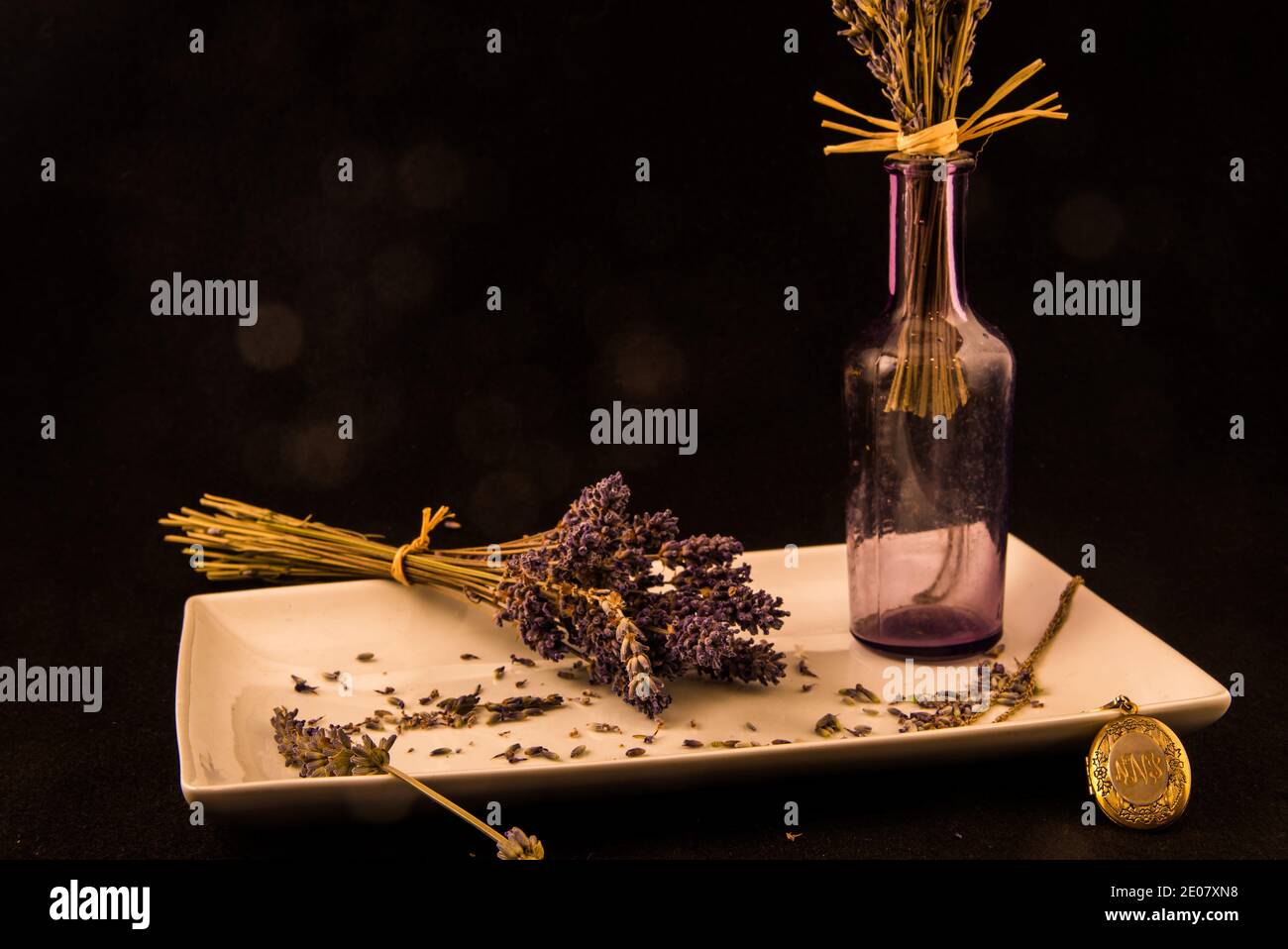 Fleurs de lavande avec bouteille de lavande et médaillon d'or sur un plateau blanc Banque D'Images