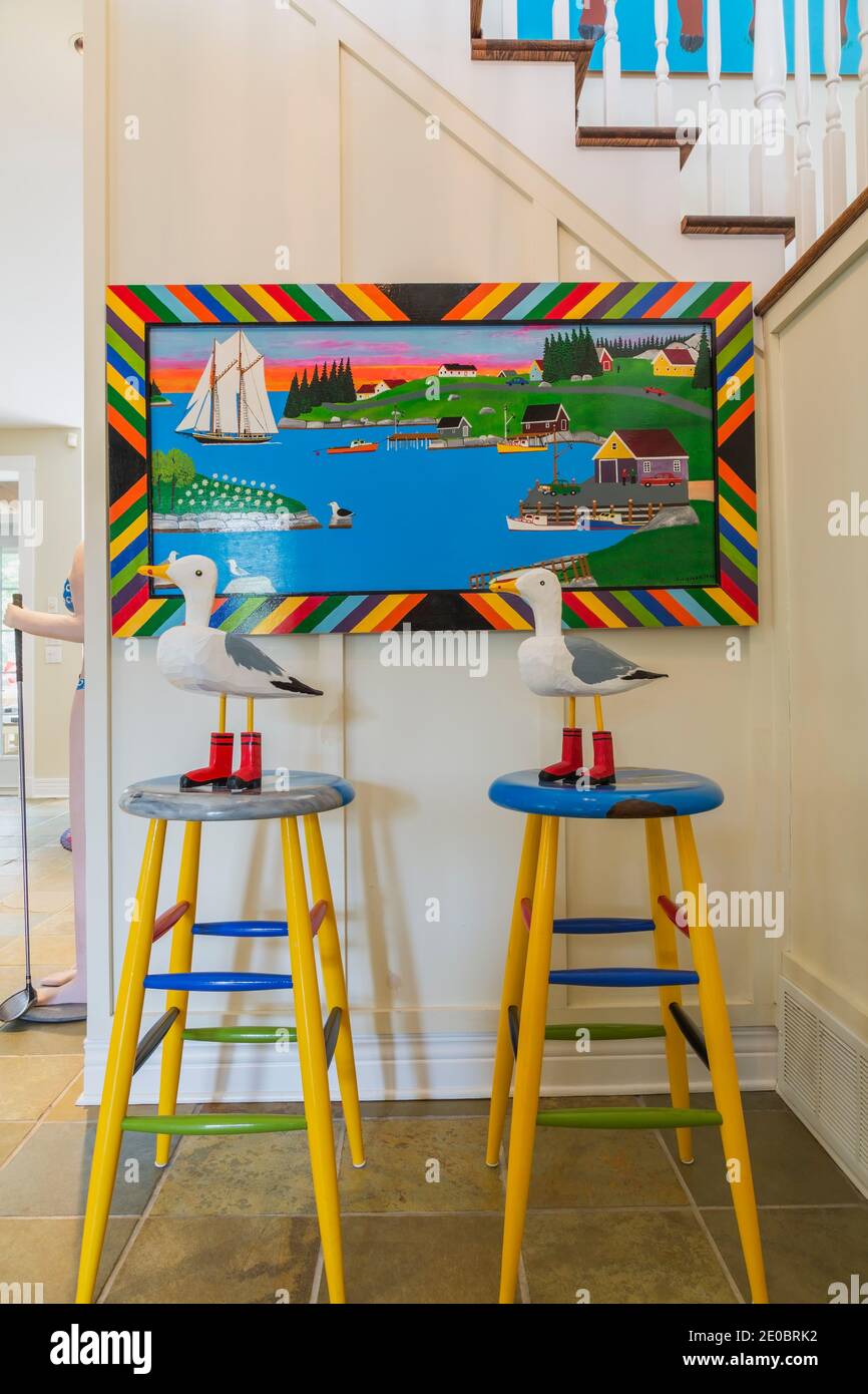 Tabourets et mouettes jaune, bleu et vert avec bottes rouges à côté de l'escalier en chêne avec balustrades peintes en blanc menant à l'étage Banque D'Images Tabourets et mouettes jaune, bleu et vert avec bottes rouges à côté de l'escalier en chêne avec balustrades peintes en blanc menant à l'étage Banque D'Images