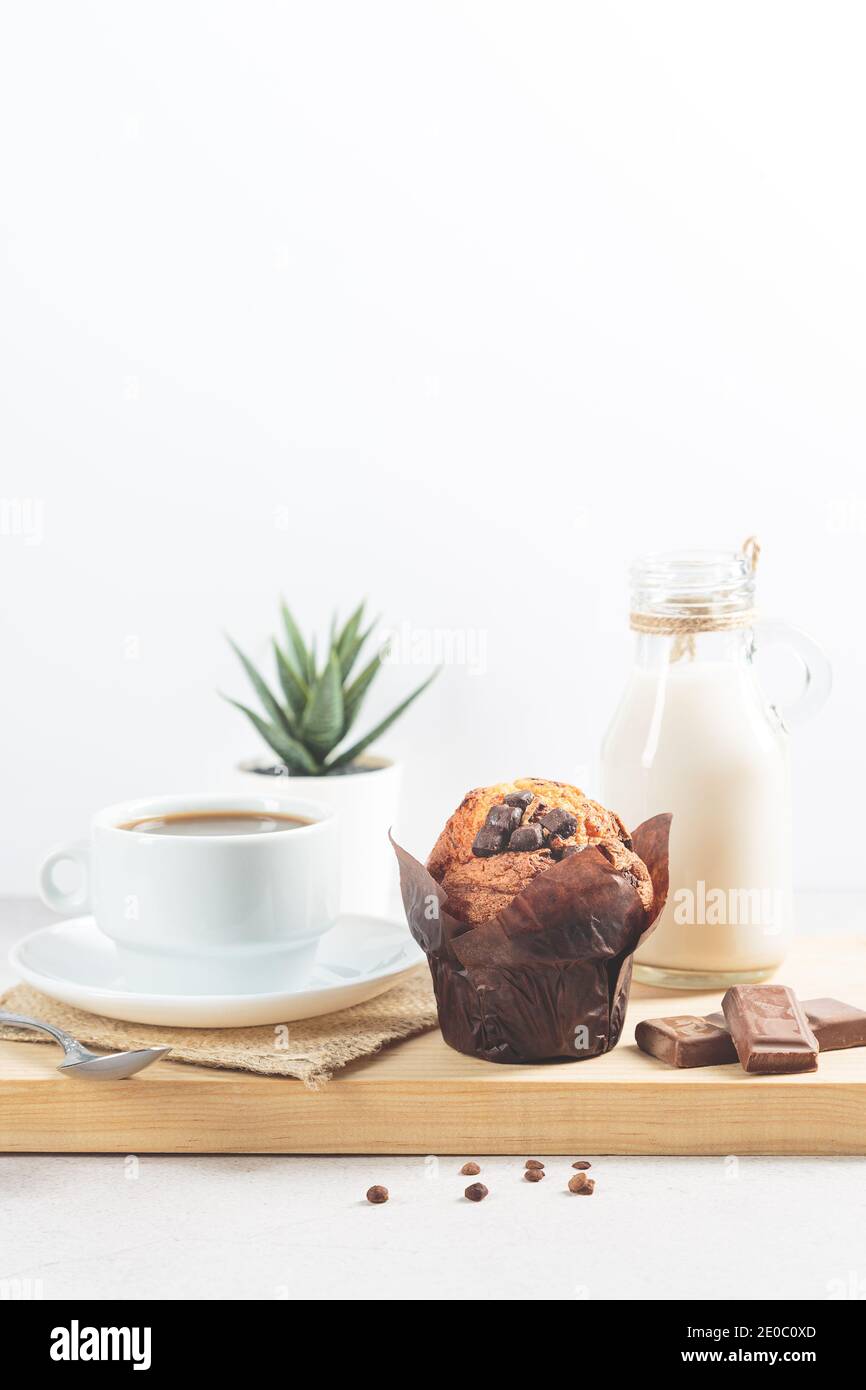 Muffin au chocolat, et une tasse de chocolate avec du lait et des copeaux de chocolat sur fond blanc. Format vertical. Banque D'Images