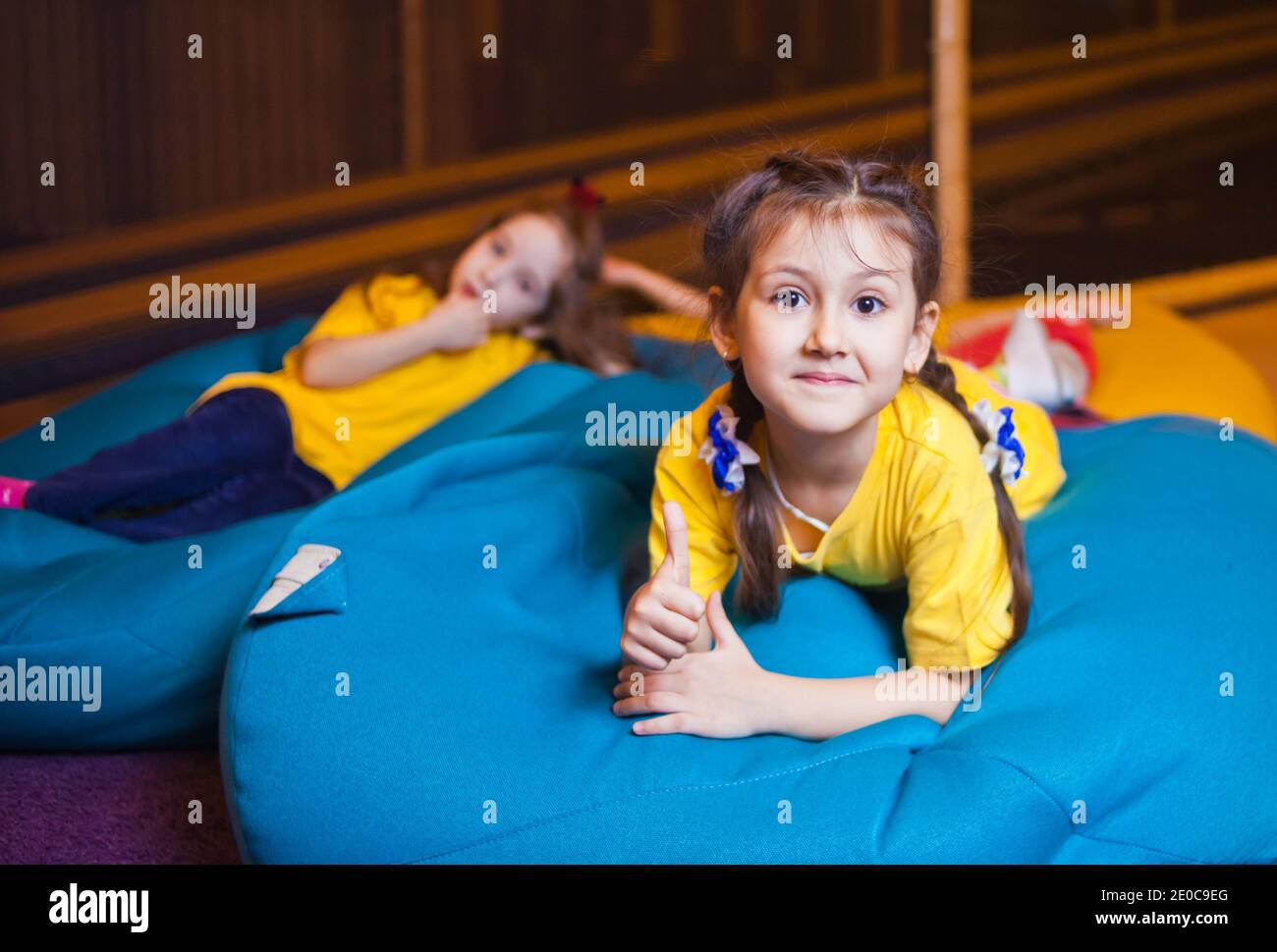 Les petites filles heureuses reposent sur le sac de chaise dans le centre de divertissement pour enfants Banque D'Images