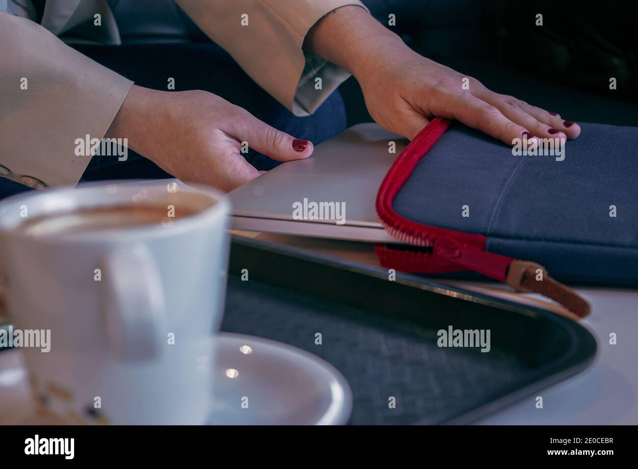 Fille prend son ordinateur de son sac pour aller au travail pendant qu'elle a le petit déjeuner pour la matinée dans un café. Fille Boss concept 2021. Banque D'Images