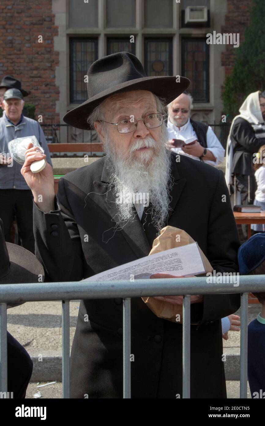 Le matin avant la Pâque, un rabbin jette ses produits de pain dans un feu de joie devant le quartier général de Lubavitch à Crown Heights, Brooklyn, New York. Banque D'Images