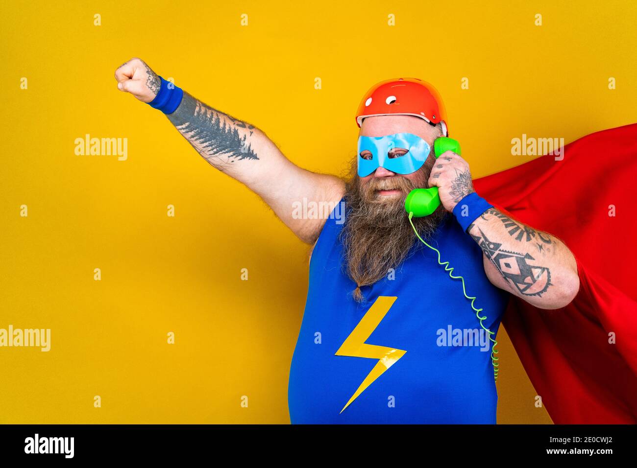 Drôle de gros homme avec le costume de super-héros agissant comme surhumain avec des pouvoirs spéciaux, portrait sur fond coloré Banque D'Images
