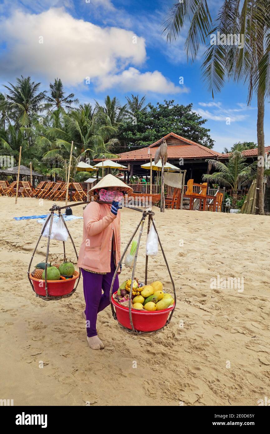 Une femme portant un chapeau conique traditionnel, appelé un non la, vendant des fruits sur la plage à Phu Quoc, Vietnam, Asie Banque D'Images