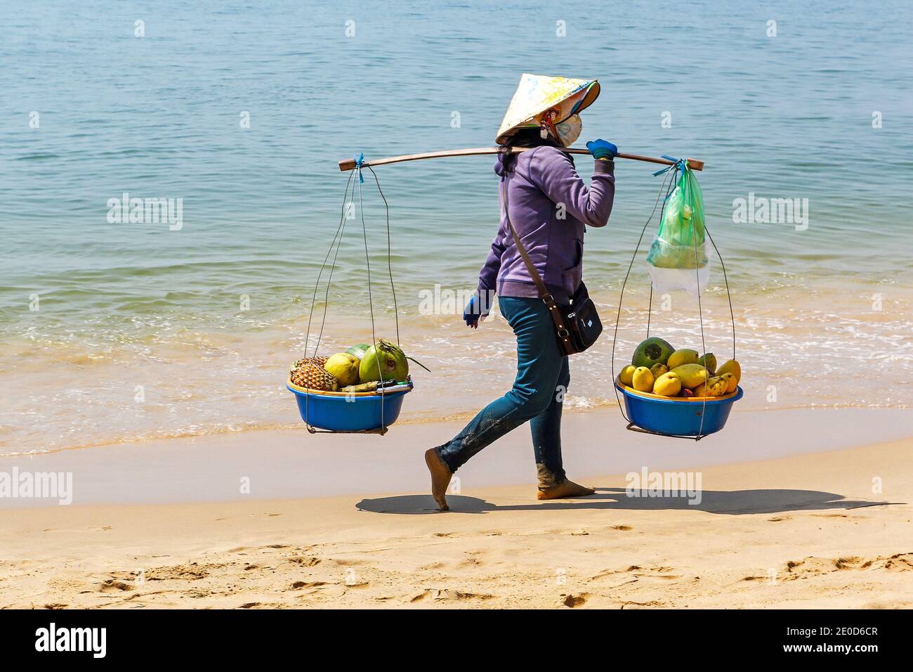 Une femme portant un chapeau conique traditionnel, appelé un non la, vendant des fruits sur la plage à Phu Quoc, Vietnam, Asie Banque D'Images