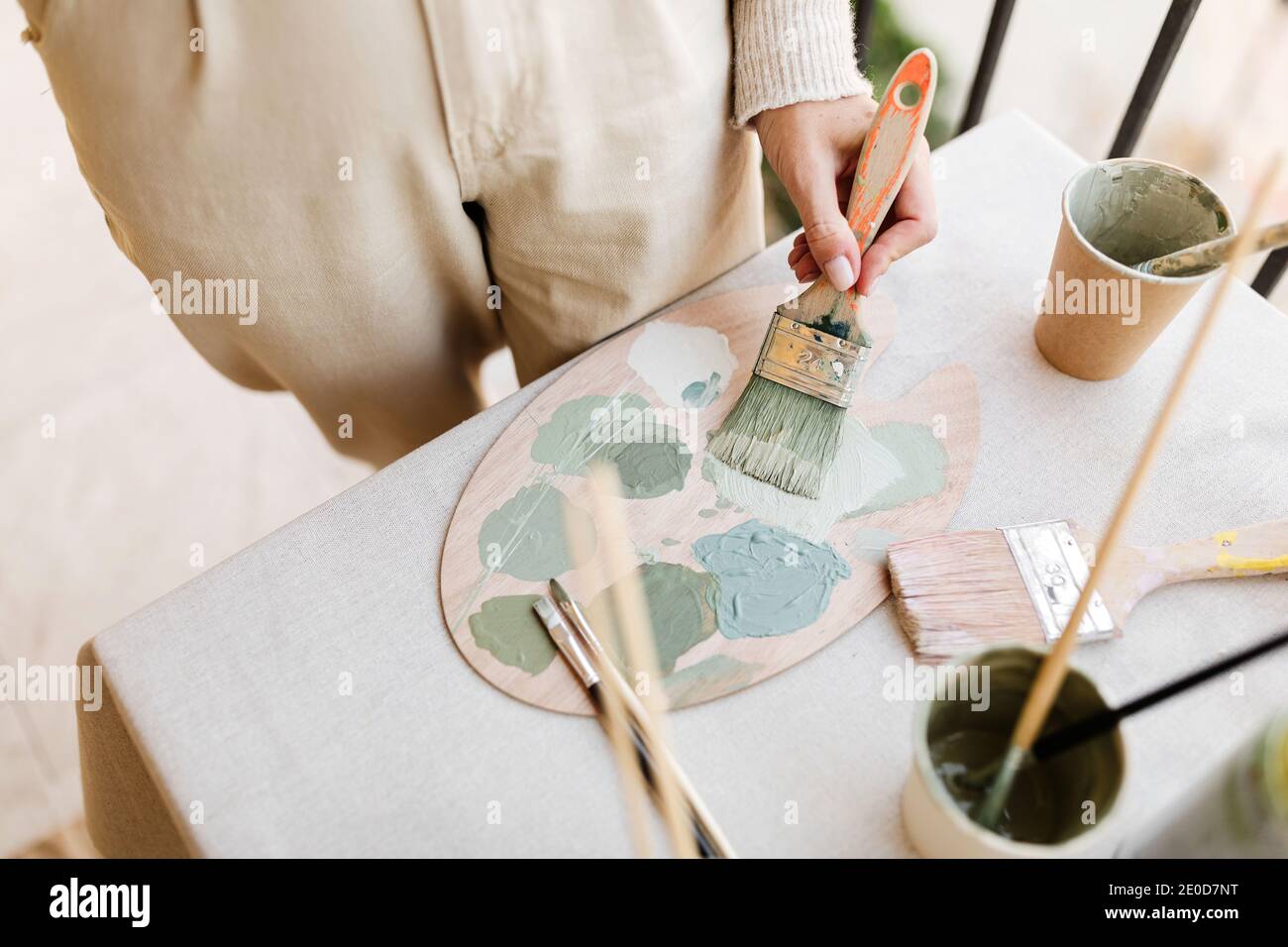 De dessus de la récolte non reconnaissable peintre femelle avec pinceau et palette de peinture mélangeant des couleurs différentes tout en travaillant dans un atelier lumineux Banque D'Images