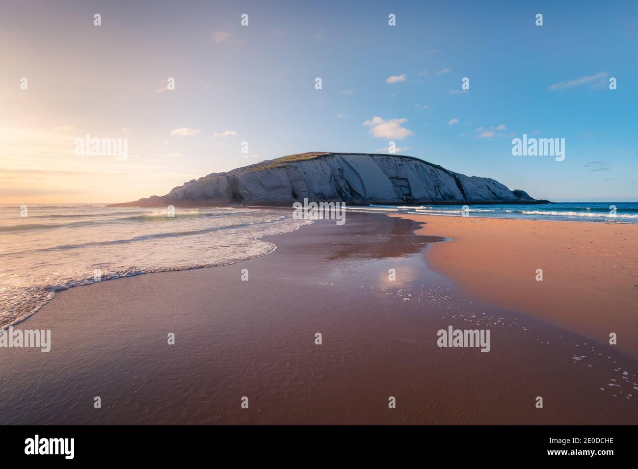 Paysage pittoresque de la falaise de craie située sur l'incroyable Playa de Plage de sable de Covachos lavant par la mer mousseuse des deux côtés Contre le coucher du soleil à Cantabr Banque D'Images