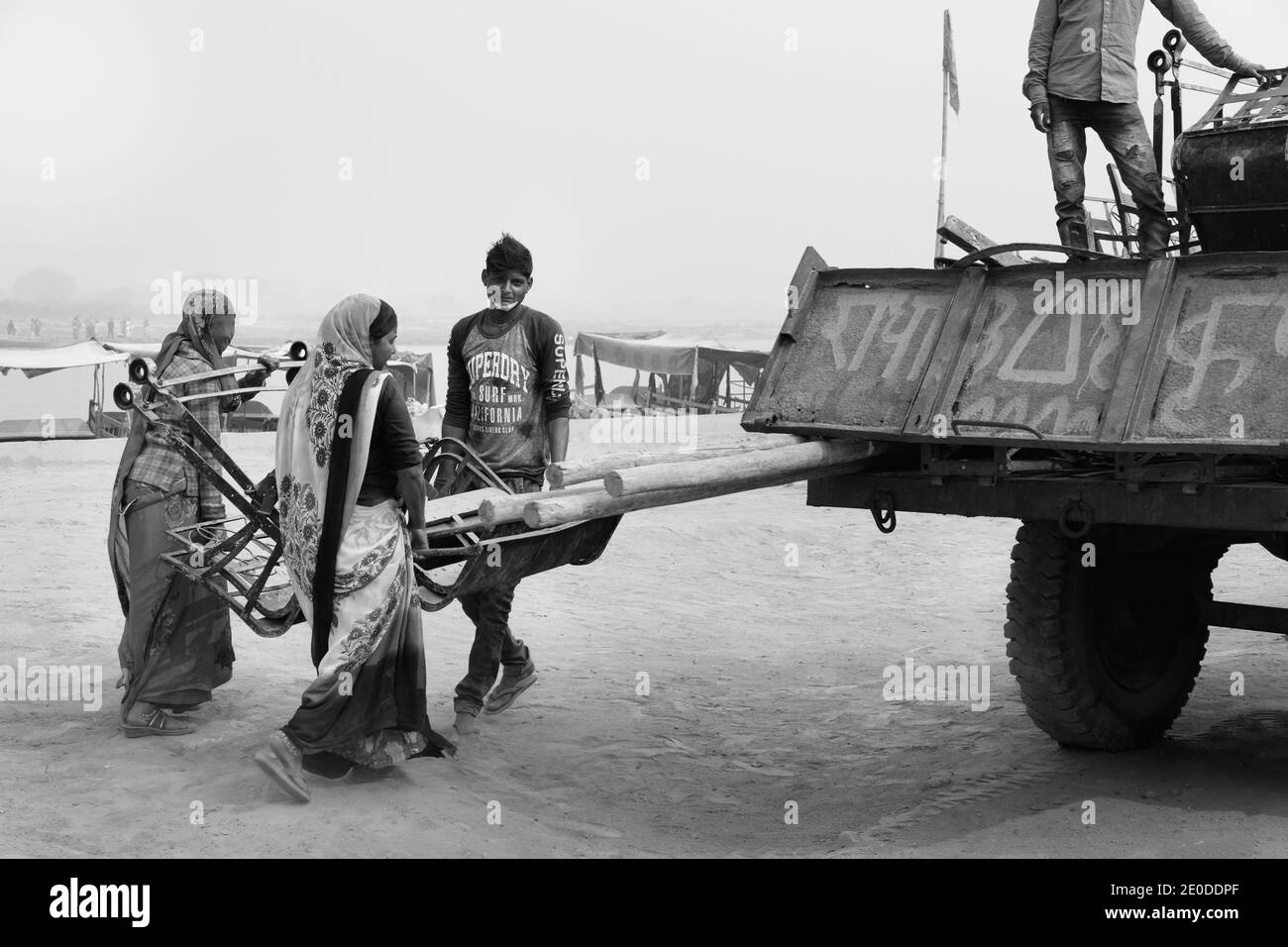 Des femmes et des hommes chargent des chaises de grande roue démantelées sur un camion d'attente lors d'une chaude journée estivale le long de la rivière Yamuna à Vrindavan, Uttar Pradesh, Inde. Banque D'Images