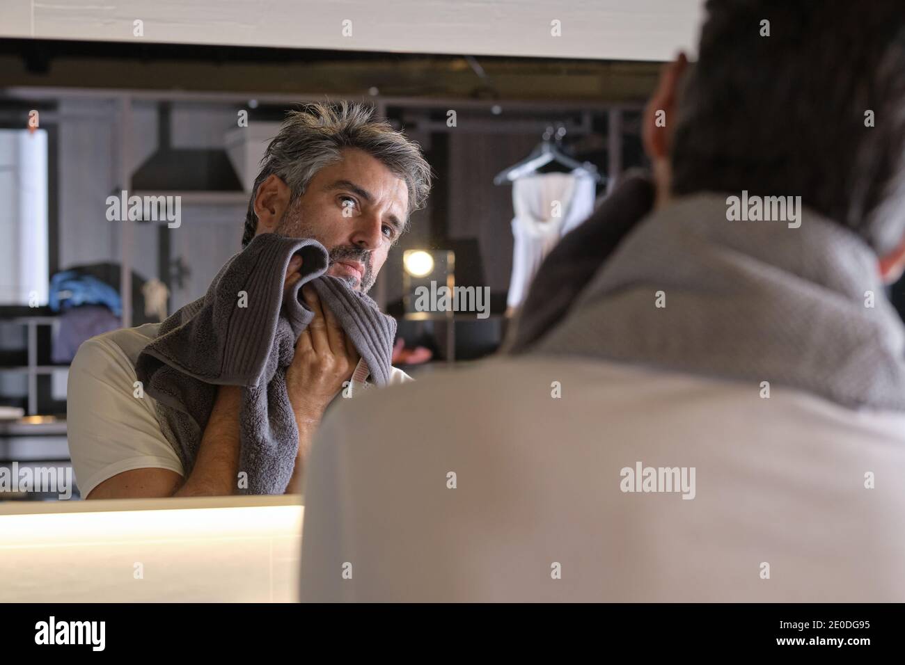 Photo de l'homme d'âge moyen avec des cheveux gris et une serviette après avoir rasé sa barbe. Banque D'Images
