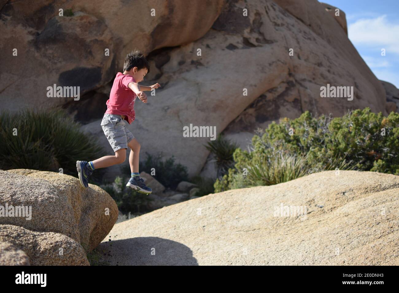 Garçon qui court sur des rochers dans le parc national de Joshua Tree Banque D'Images