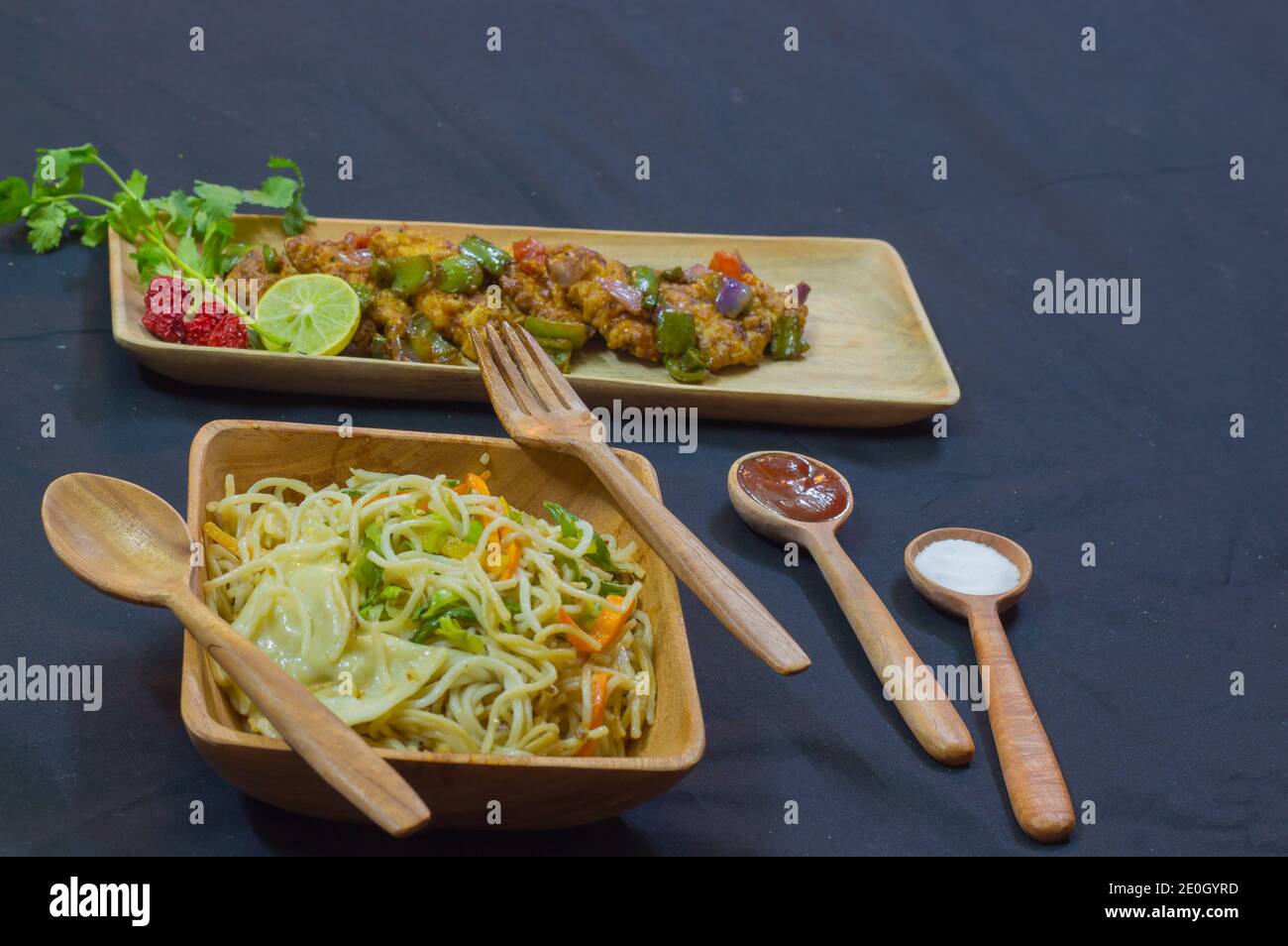 poulet au chili et nouilles servis sur des assiettes en bois avec une cuillère et une fourchette. délicieux plats chinois pour l'arrière-plan de l'espace de copie. matériel publicitaire. Banque D'Images