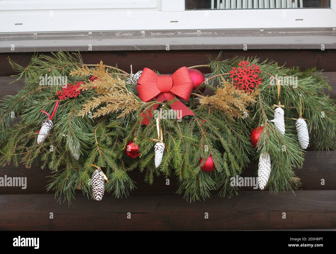 Décoration de fenêtre de Noël. Ancienne maison en brique. Boules rouges et branches vertes. Concept - Noël, nouvel an. Banque D'Images
