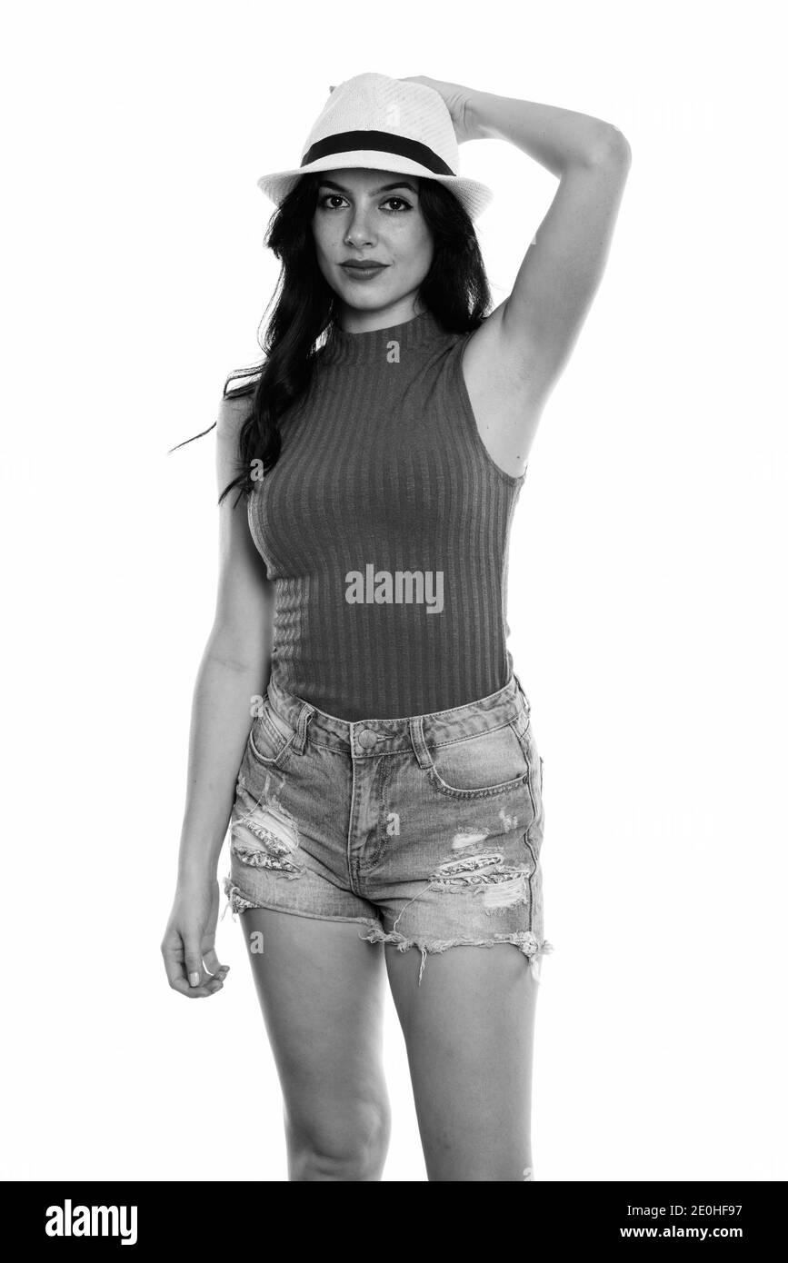 Studio shot of young woman standing belle espagnole tout en tenant tête à chapeau Banque D'Images