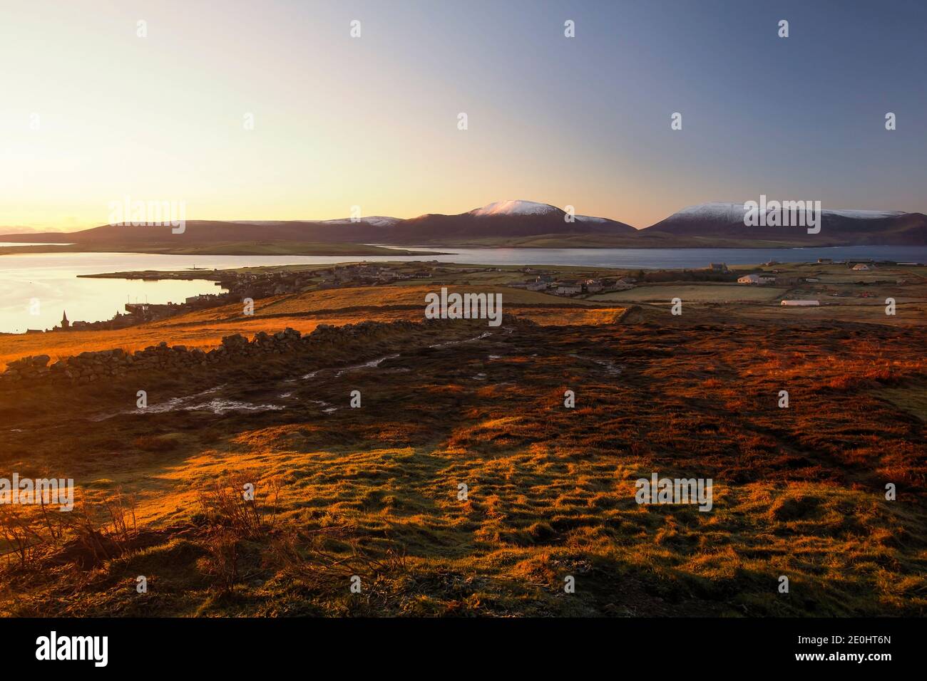 Vue aérienne de la ville de Stromness, dans le nord de l'Écosse, sur les îles Orcades avec lumière du lever du soleil et neige sur les collines Banque D'Images