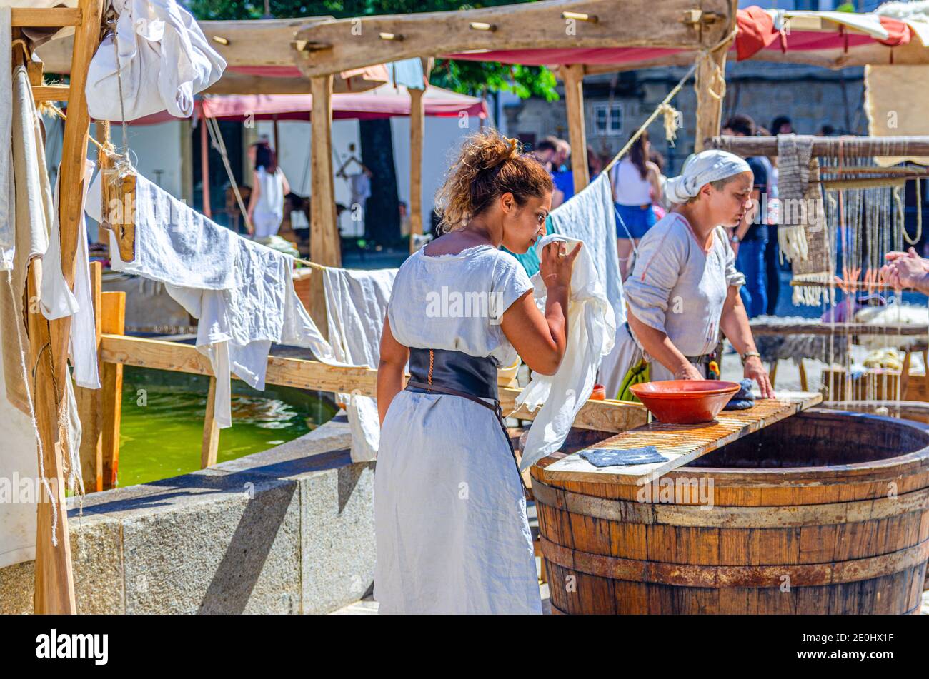 Guimaraes, Portugal, 24 juin 2017: Maîtresse vérifiant le linge de maison, femme de ménage dans les vieux vêtements traditionnels près du canon en bois dans le centre historique, scène médiévale pendant la fête de la ville Banque D'Images