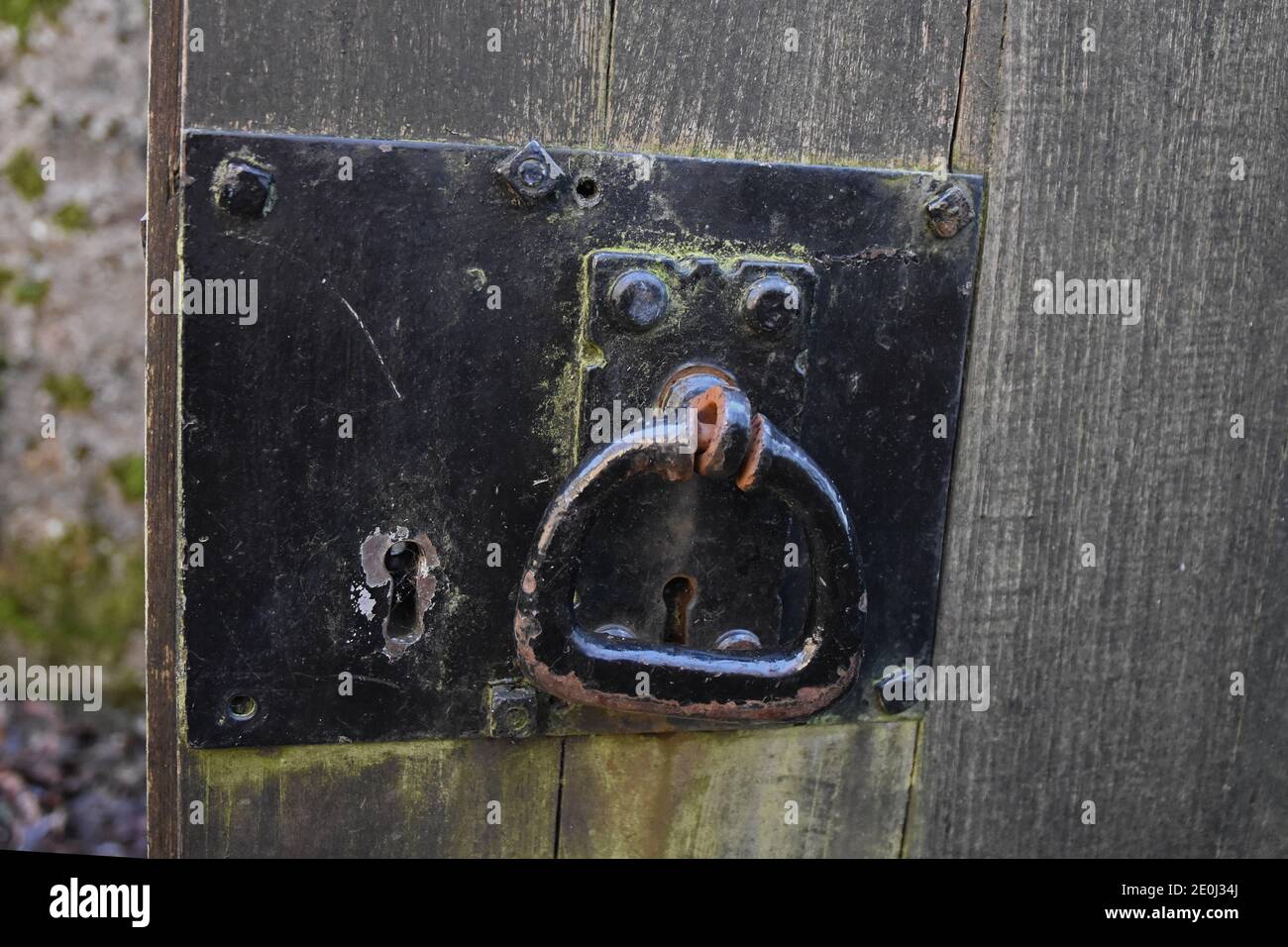 Ancienne serrure en métal noir avec trou de serrure et poignée rotative sur une porte en bois abîmé. Arrière-plan flou. Prise à Culross, Fife, Écosse, Royaume-Uni Banque D'Images