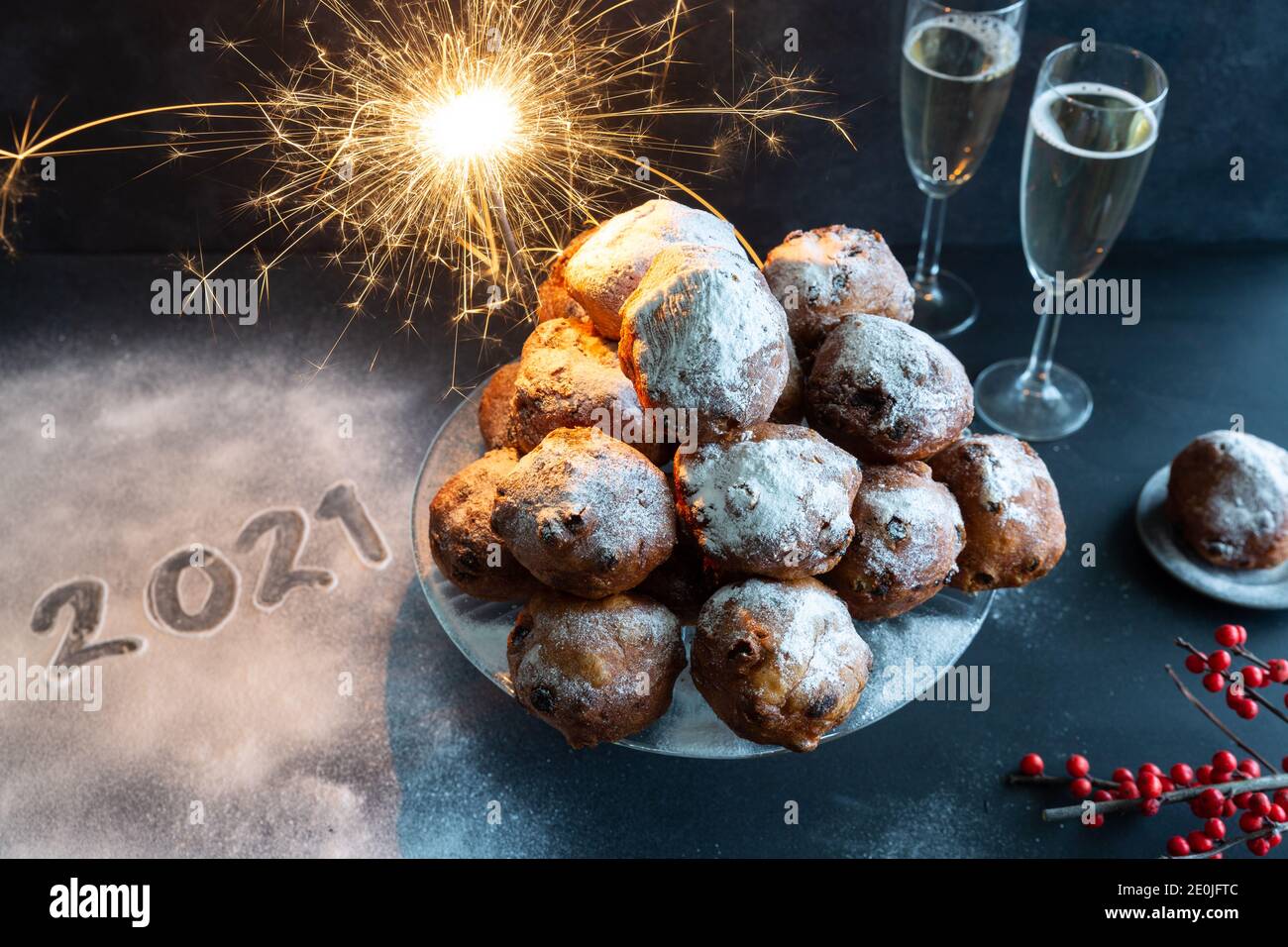 Bonne année avec le sucre glace écrit de l'année 2021 À côté d'un bol d'oliebollen (beignets de pâte hollandais) avec des sparkles et deux verres de champagne Banque D'Images