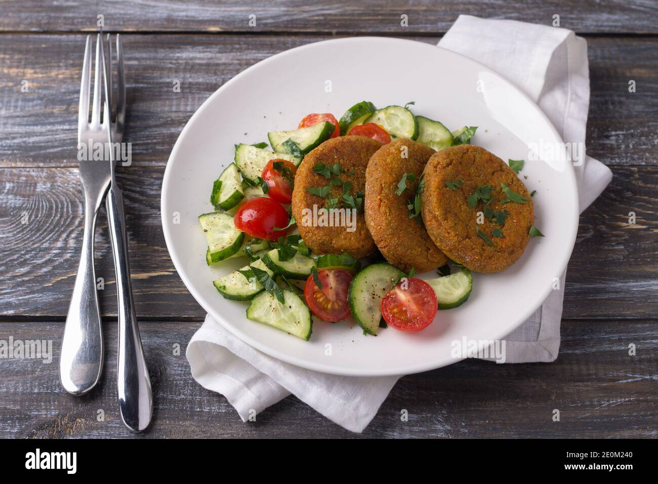 Côtelettes de carottes à l'amarante, salade de concombres frais et tomates sur une table en bois. Délicieux plats maison sains Banque D'Images