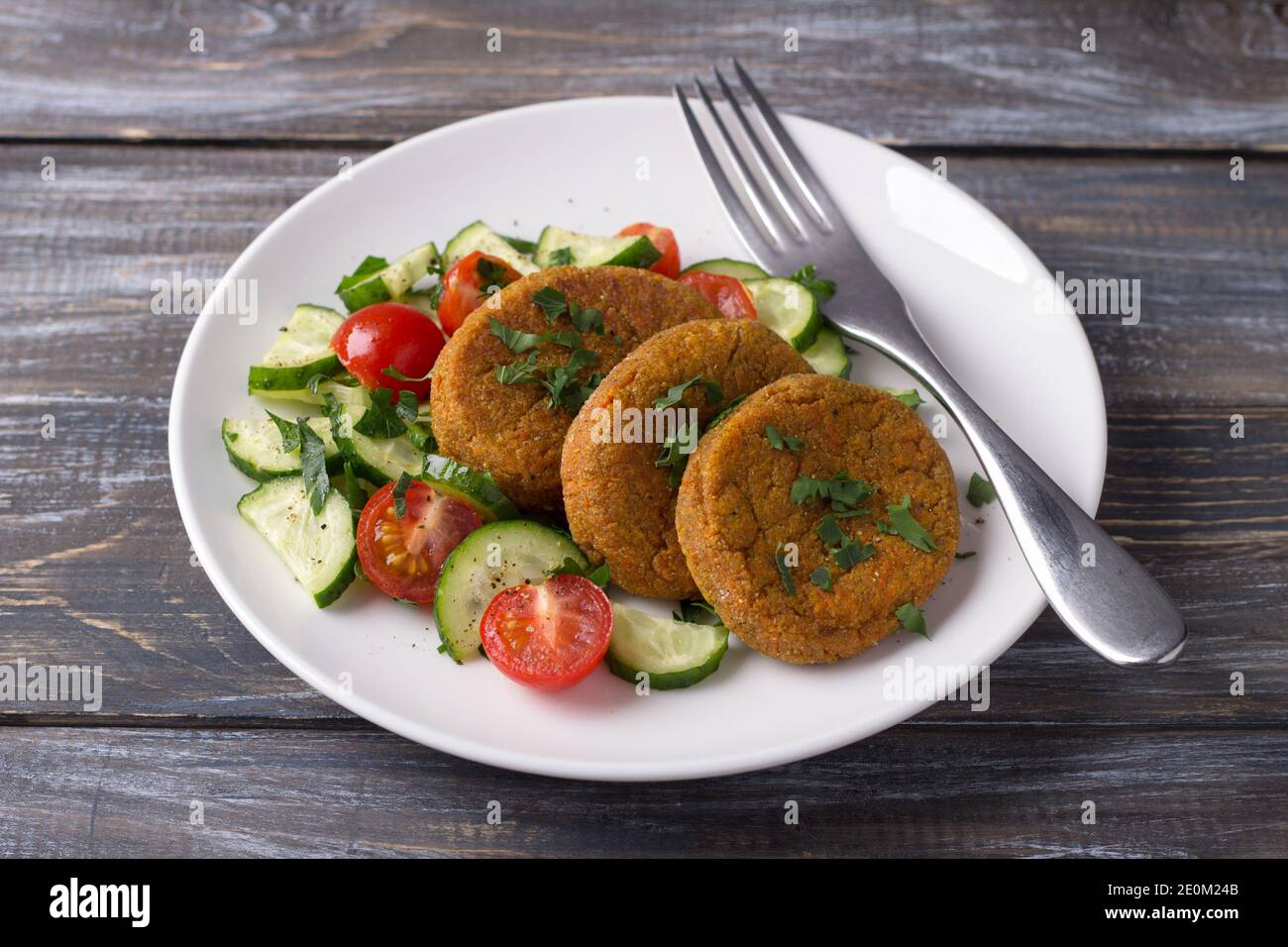 Côtelettes de carottes à l'amarante, salade de concombres frais et tomates sur une table en bois. Délicieux plats maison sains Banque D'Images