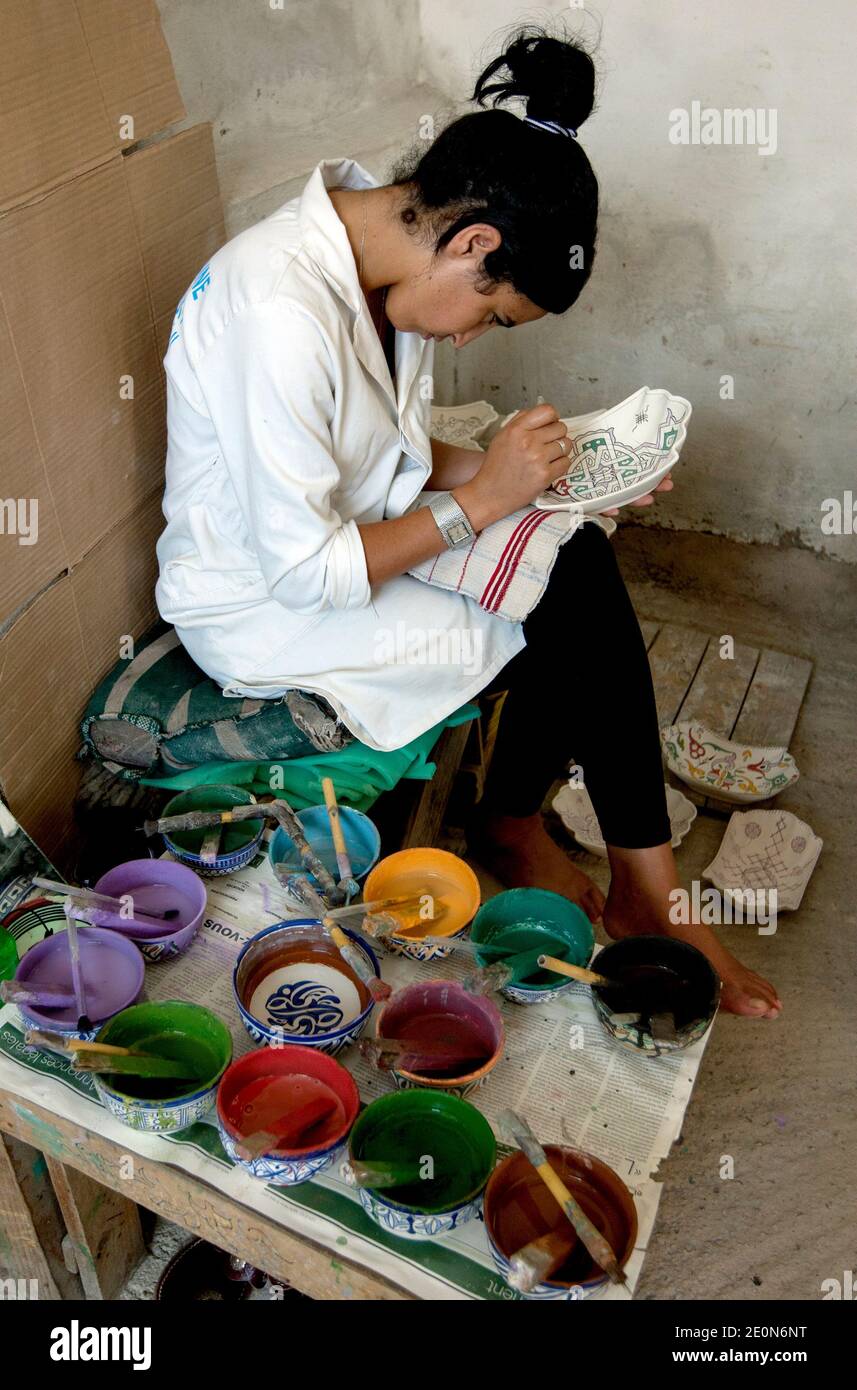 Un ouvrier commence le processus de peinture de dessins sur un bol en argile à l'usine Art Naji à Fès, au Maroc. Banque D'Images