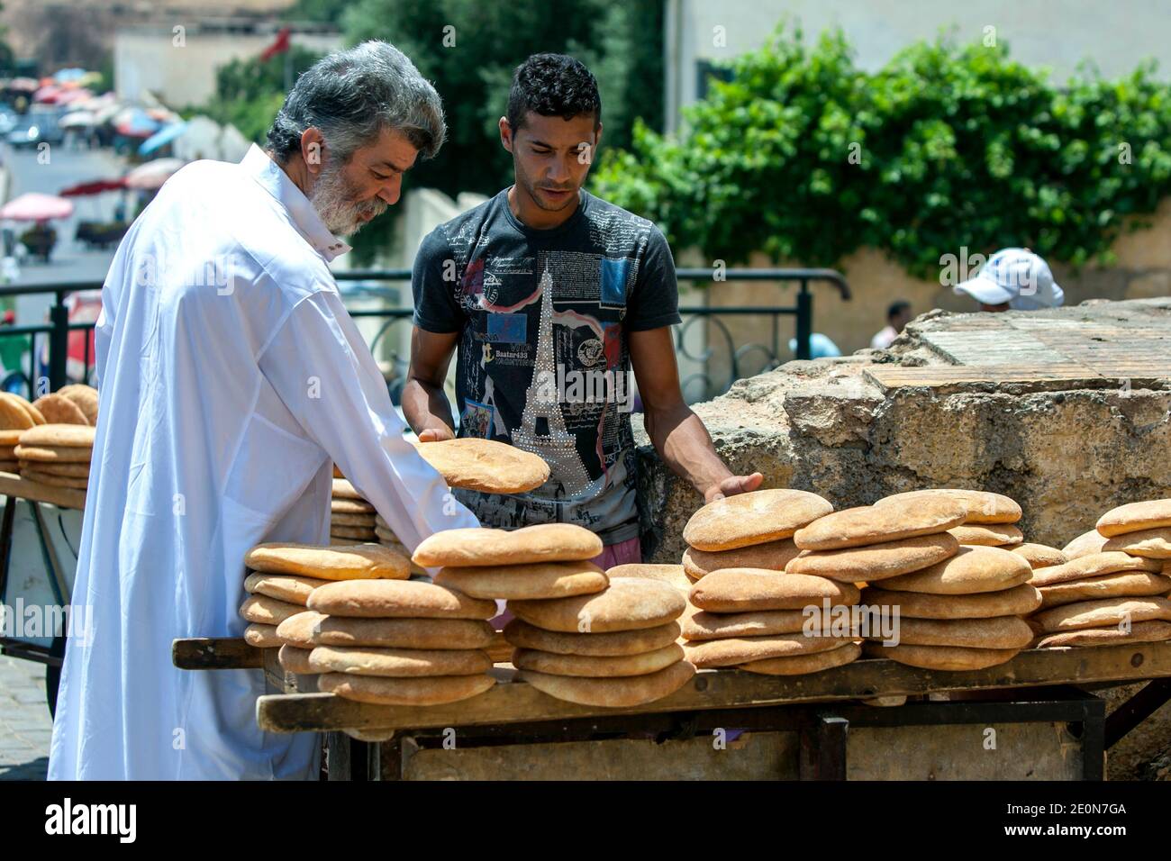 Un homme inspecte un chariot chargé de pain plat vendu à côté de la place Lahdim à Meknes. Meknes est l'une des quatre villes impériales du Maroc. Banque D'Images