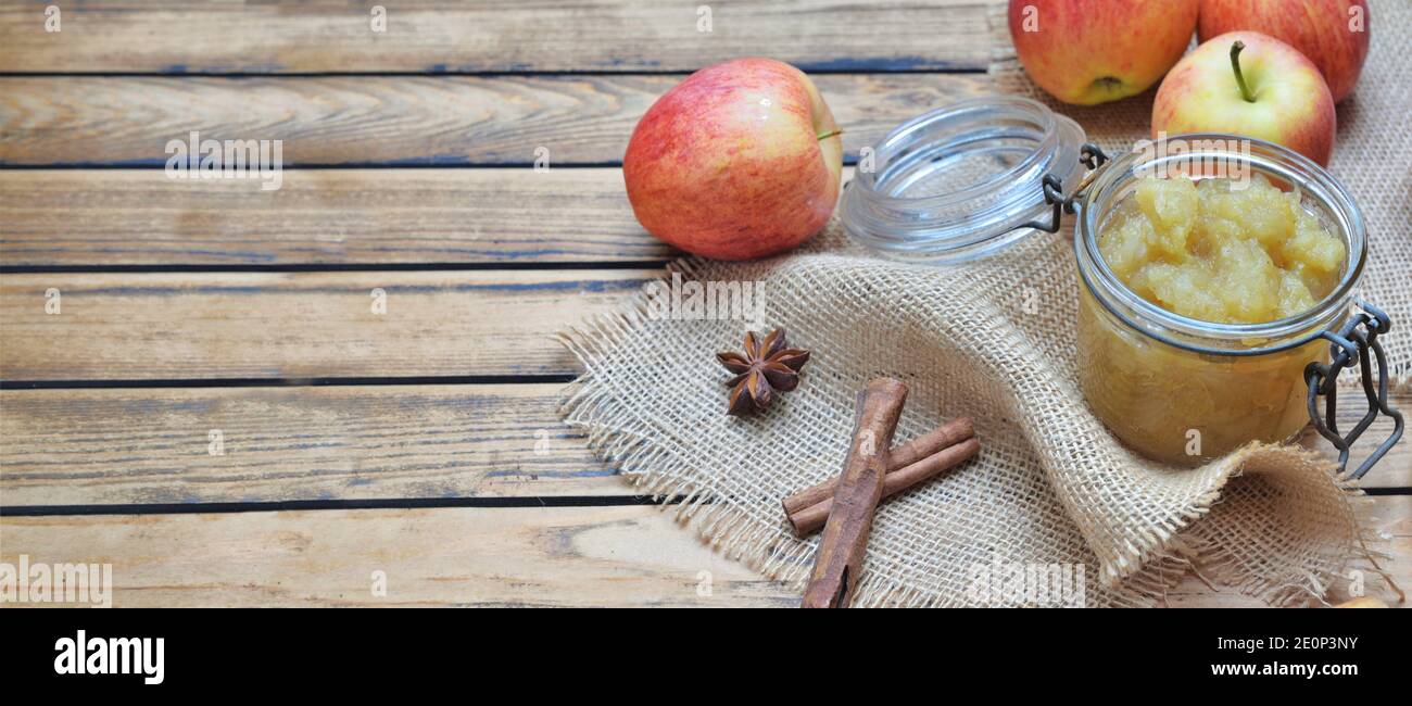 vue panoramique sur une compote maison dans un pot en verre avec pommes rouges et épices sur une table de fond Banque D'Images