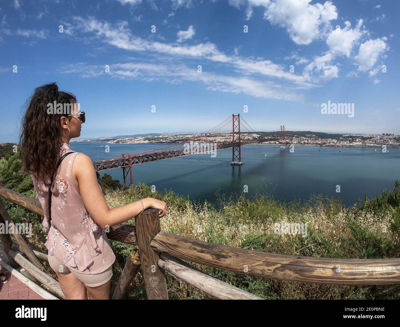 Pont suspendu rouge de Lisbonne par une journée ensoleillée avec la ville en arrière-plan pont portugais semblable au pont de San Francisco, avec une femme à t Banque D'Images