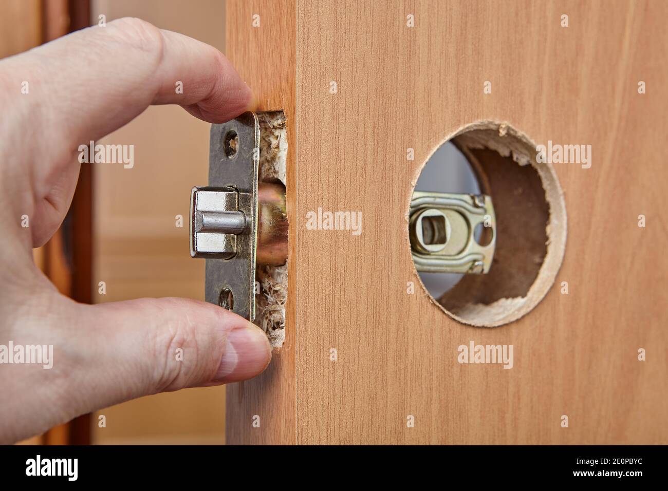 Lors du montage d'une serrure avec une poignée, le serrurier passe la  plaque de verrouillage avec l'ensemble à travers l'alésage de bord de la  porte intérieure en bois Photo Stock - Alamy